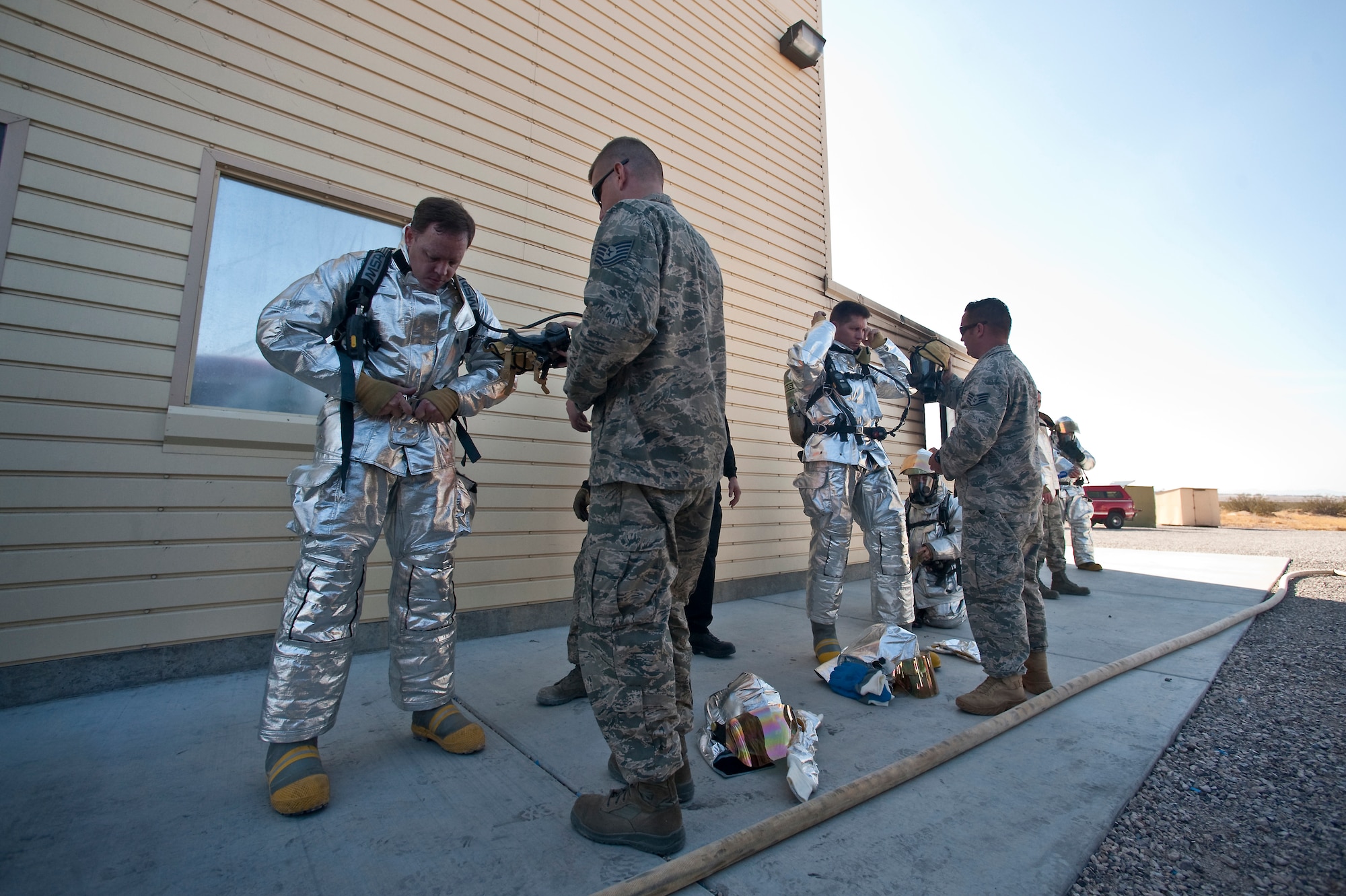NELLIS AIR FORCE BASE, Nev. -- Tech. Sgt. Michael Wobser and Staff Sgt. Christopher Pennock, 99th Civil Engineer Squadron firefighters, conduct buddy checks with Col. Steven Garland, 99th Air Base Wing commander and Brig. Gen. David Thompson, U.S Air Force Warfare Center vice commander before fighting a simulated structural fire at the Nellis live-fire training facility Oct. 18. The 99th Civil Engineer Squadron and fire emergency services flight invited Nellis senior leaders to a live-fire aircraft and structural exercise so they could experience some of the challenges firefighters encounter during real-world situations. (U.S. Air Force photo by Tech. Sgt. Michael R. Holzworth)(Released)