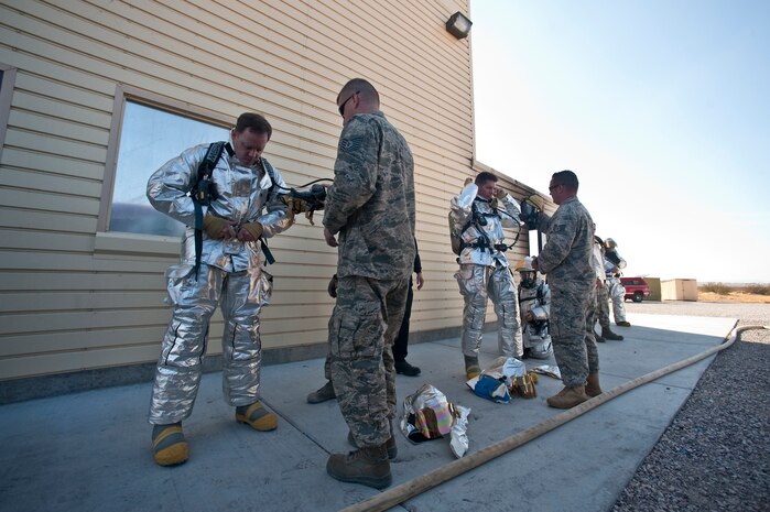 NELLIS AIR FORCE BASE, Nev. -- Tech. Sgt. Michael Wobser and Staff Sgt. Christopher Pennock, 99th Civil Engineer Squadron firefighters, conduct buddy checks with Col. Steven Garland, 99th Air Base Wing commander and Brig. Gen. David Thompson, U.S Air Force Warfare Center vice commander before fighting a simulated structural fire at the Nellis live-fire training facility Oct. 18. The 99th Civil Engineer Squadron and fire emergency services flight invited Nellis senior leaders to a live-fire aircraft and structural exercise so they could experience some of the challenges firefighters encounter during real-world situations. (U.S. Air Force photo by Tech. Sgt. Michael R. Holzworth)(Released)
