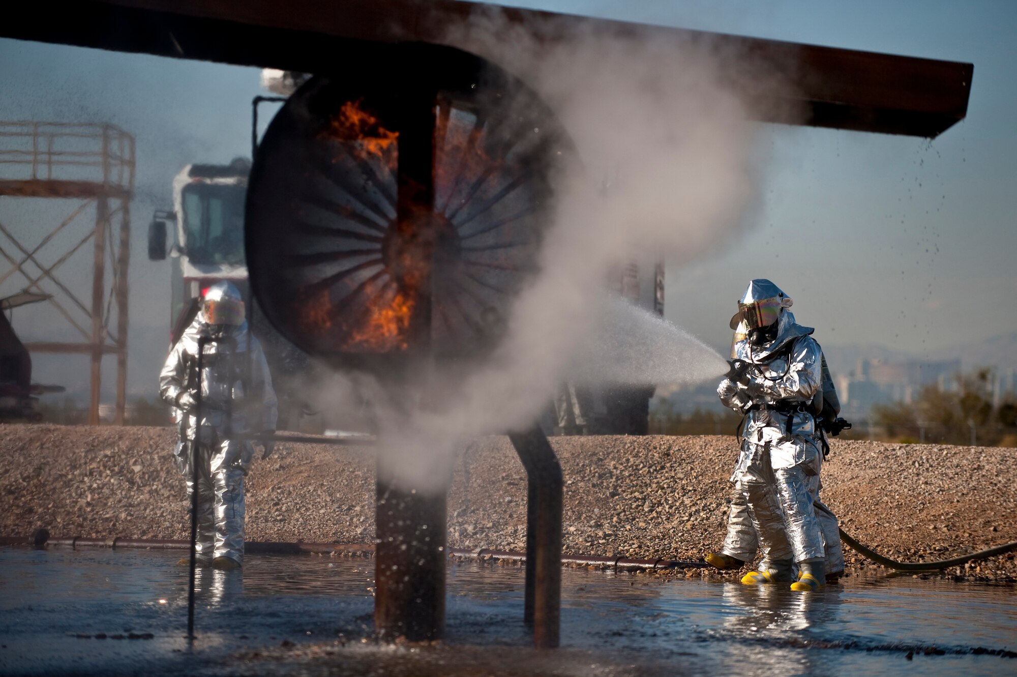 NELLIS AIR FORCE BASE, Nev. --  Brig. Gen. David Thompson, U.S Air Force Warfare Center vice commander, works with Senior Airman Nathan Aguilera and Senior Airman Michael Nieman, 99th Civil Engineer Squadron Fire Department firefighters, on the proper use of the buddy system while fighting a simulated aircraft fire at the Nellis live-fire training facility Oct. 18. The 99th Civil Engineer Squadron and fire emergency services flight invited Nellis senior leaders to a live-fire aircraft and structural exercise so they could experience some of the challenges firefighters encounter during real-world situations. (U.S. Air Force photo by Tech. Sgt. Michael R. Holzworth)(Released)