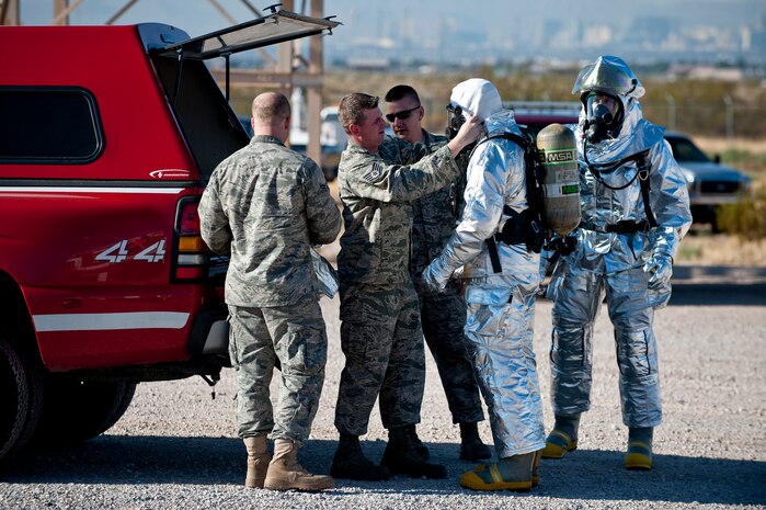 NELLIS AIR FORCE BASE, Nev. -- Airman from the 99th Civil Engineer Squadron Fire Department conduct  a buddy check on Col. Steven Garland, 99th Air Base Wing commander and Brig. Gen. David Thompson, U.S Air Force Warfare Center vice commander, before fighting a simulated aircraft fire at the Nellis live fire training facility Oct. 18. The 99th Civil Engineer Squadron and fire emergency services flight invited Nellis senior leaders to a live-fire aircraft and structural exercise so they could experience some of the challenges firefighters encounter during real-world situations. (U.S. Air Force photo by Tech. Sgt. Michael R. Holzworth)(Released)
