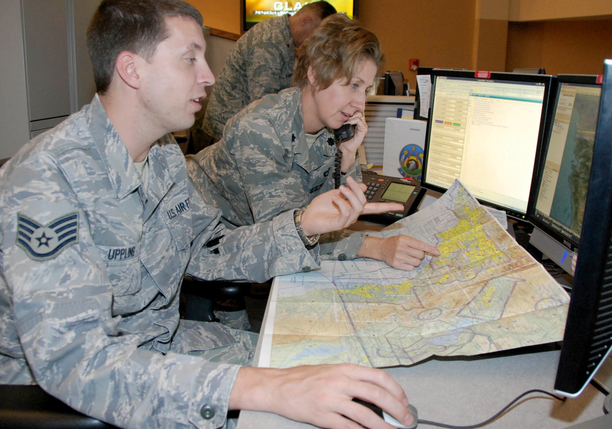 Staff Sgt. Christopher Uppling (left) and Lt. Col. Julie Eubanks establish communications with their counterparts at Mexico's Rescue Coordination Center Oct. 15, 2010, at Tyndall Air Force Base, Fla., during a search for a missing airplane near the U.S.-Mexico border. Both are controllers with the Air Force Rescue Coordination Center at Tyndall AFB and assisted in the coordination of locating the fatal crash site. (U.S. Air Force photo/Capt. Jared Scott)