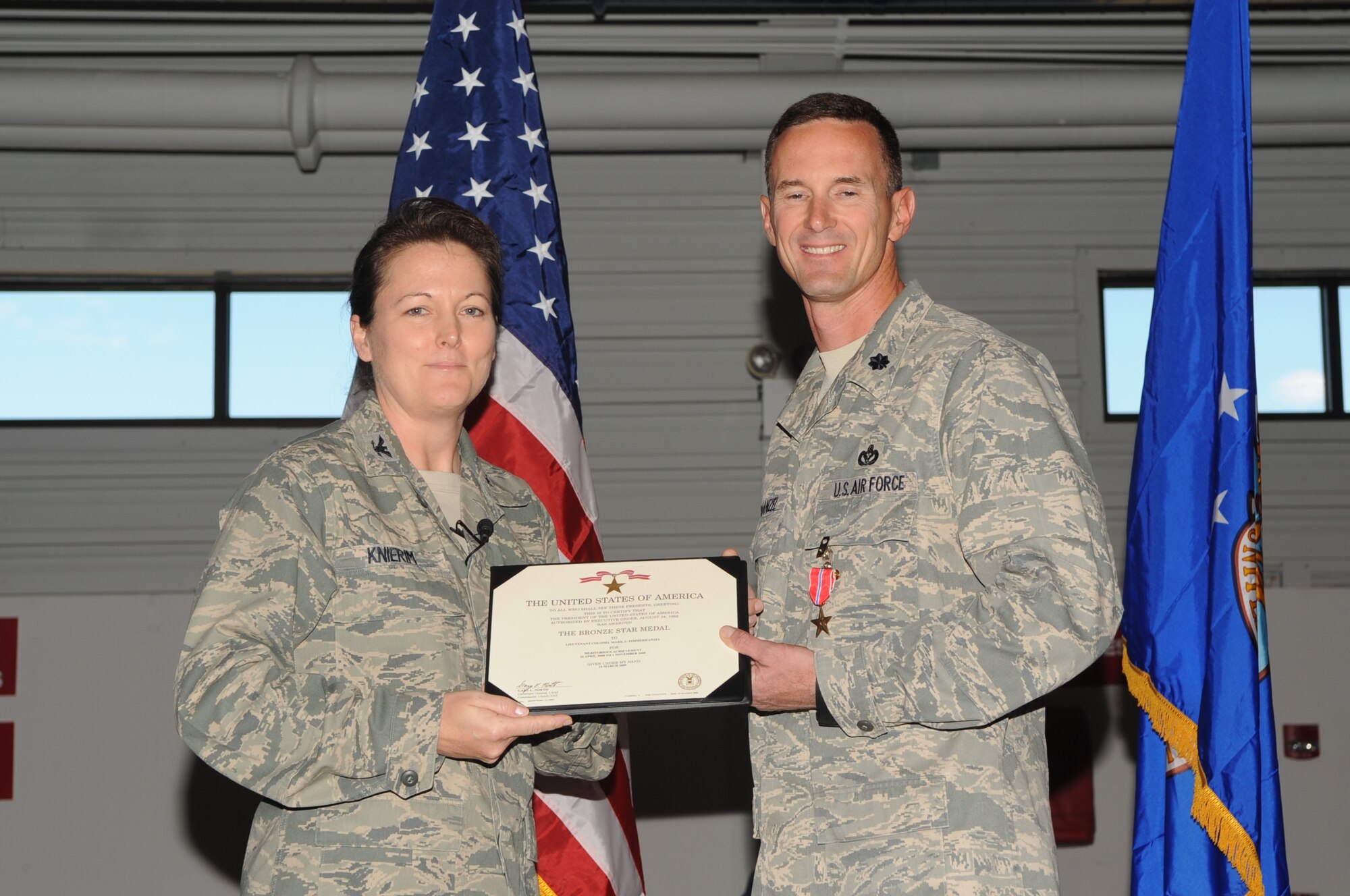 Col. Tammy M. Knierim (left), 319th Mission Support Group commander, presents Lt. Col. Mark A. Zimmerhanzel, 319th Civil Engineer Squadron commander, with the Bronze Star Medal Oct. 19 during a commander’s call at Liberty Square on Grand Forks Air Force Base, N.D. Colonel Zimmerhanzel was awarded the Bronze Star for his meritorious achievements while deployed in support of Operation Iraqi Freedom from April 26, 2008, to Nov. 1, 2008, as the 732nd Expeditionary Civil Engineer Squadron commader. (U.S. Air Force photo by Senior Airman Amanda N. Stencil)