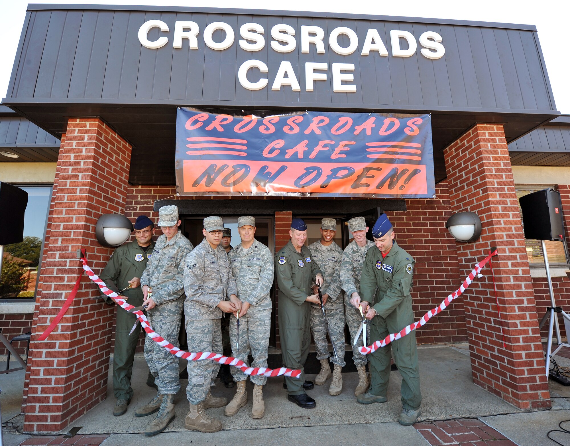Base leaders gather with Airmen to cut the ceremonial ribbon during the Crossroads Café grand opening Oct. 15. The opening of the new café location coincides with Comprehensive Airman Fitness, promoting positive behaviors and holistic health. (U.S. Air Force photo by Staff Sgt. Chris Willis)