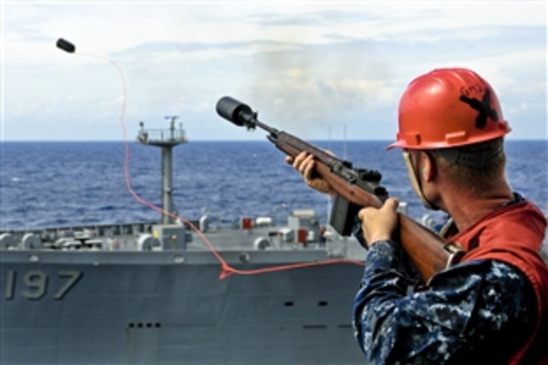A U.S. Navy sailor serving as an aviation ordnanceman fires a shot line from the starboard side of the amphibious assault ship USS Essex to the Military Sealift Command fleet replenishment oiler USNS Pecos before an underway replenishment in Palawan Passage in the Pacific Ocean, Oct. 18, 2010.