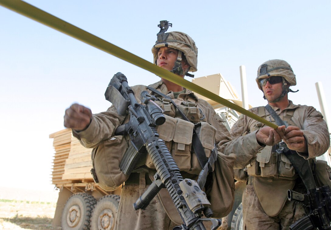 Cpl. Ernesto Garibay, an electrical engineer attached to 2nd Battalion, 9th Marine Regiment, and Cpl. Phillip J. Hargrave, a combat engineer attached to 2/9, carefully measure the perimeter of a new patrol base during a clear, hold, and build operation, Oct. 21, in Northern Marjah, Afghanistan. The main purpose of the operation was established security for the construction of a new patrol base while conducting searches of local’s compounds in the area. They received no enemy resistance.