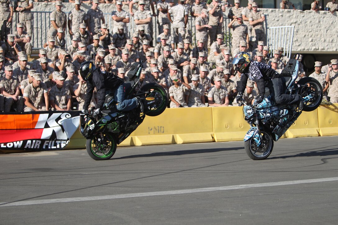 Tony Carbajal [left], and Alex Flores, freestyle motorcycle stunt riders, who performed at the Marine Corps Communication-Electronics School’s annual Safety Fair, fly past an excited crowd of MCCES students Oct. 22, 2010 by their barracks. Aside from the dazzling performance, the students also received well-needed lessons in safety.::r::::n::