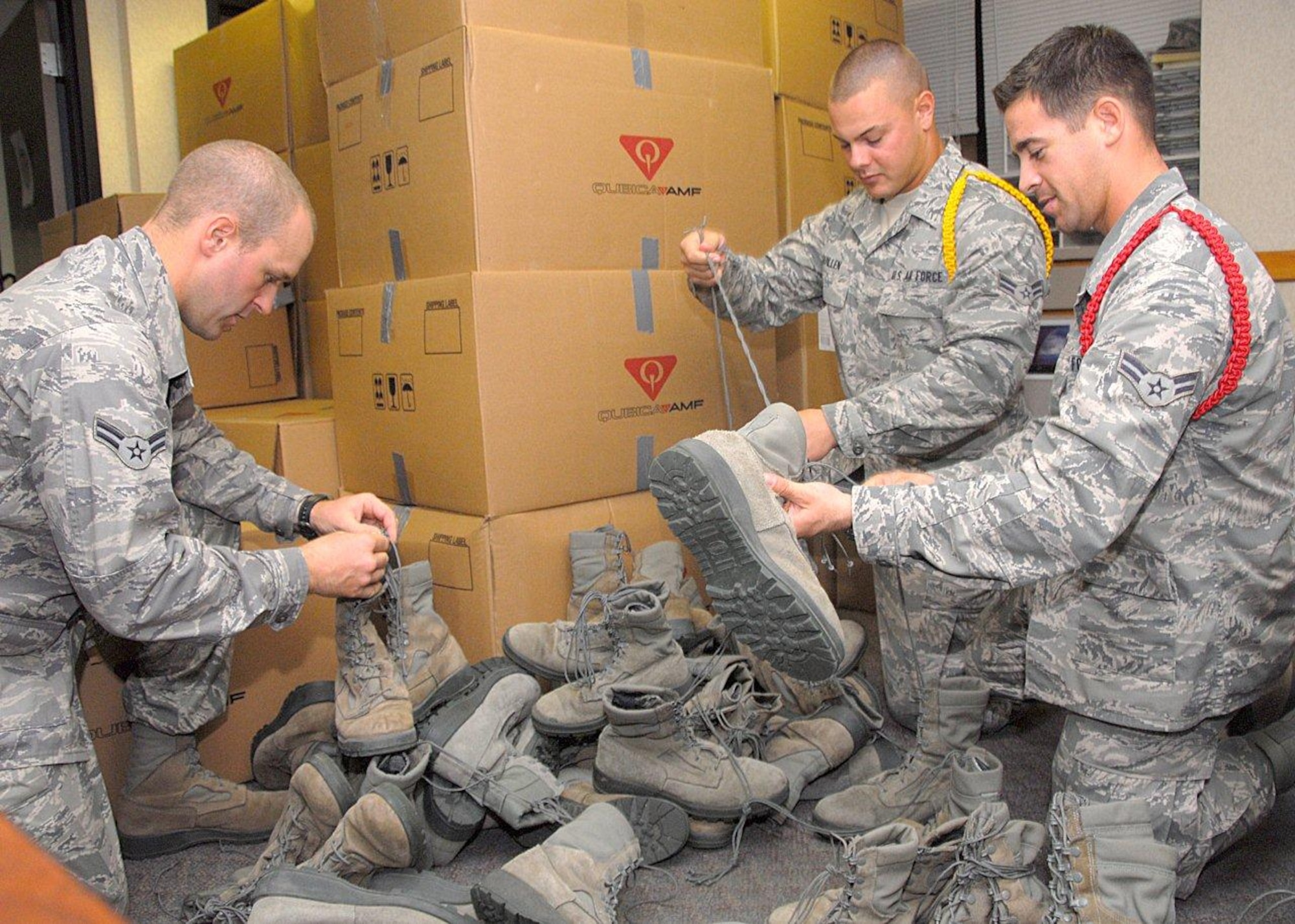 Airman 1st Class Sean Johnson (left), A1C Matthew Quillen (back), and Airman 1st Class Cody Reynon (right), Airmen in Training, tie boots together before packing them in boxes and donating them to the Sonshine House in Wichita Falls Oct. 15. With help from Team Sheppard members, Airman Johnson was able to collect more than 450 pairs of boots in one weekend for this donation. (U.S. Air Force photo/Harry Tonemah) 