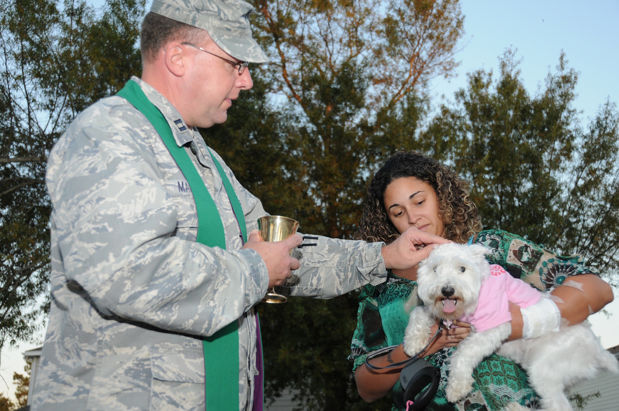 Chaplain (Capt.) CharlesMallory blesses Stephanie Cyr’s miniature schnauzer, Winter, Sunday in East Falcon Park. Mrs. Cyr’s husband is Tech Sgt. Nathan Cyr, 332nd Training Squadron. The annual ecumenical blessing acknowledges the importance pets play in the lives of their owners. There were 28 pets blessed in Bay Ridge, East Falcon andWest Falcon Parks. (U.S. Air Force photo by Kemberly Groue)