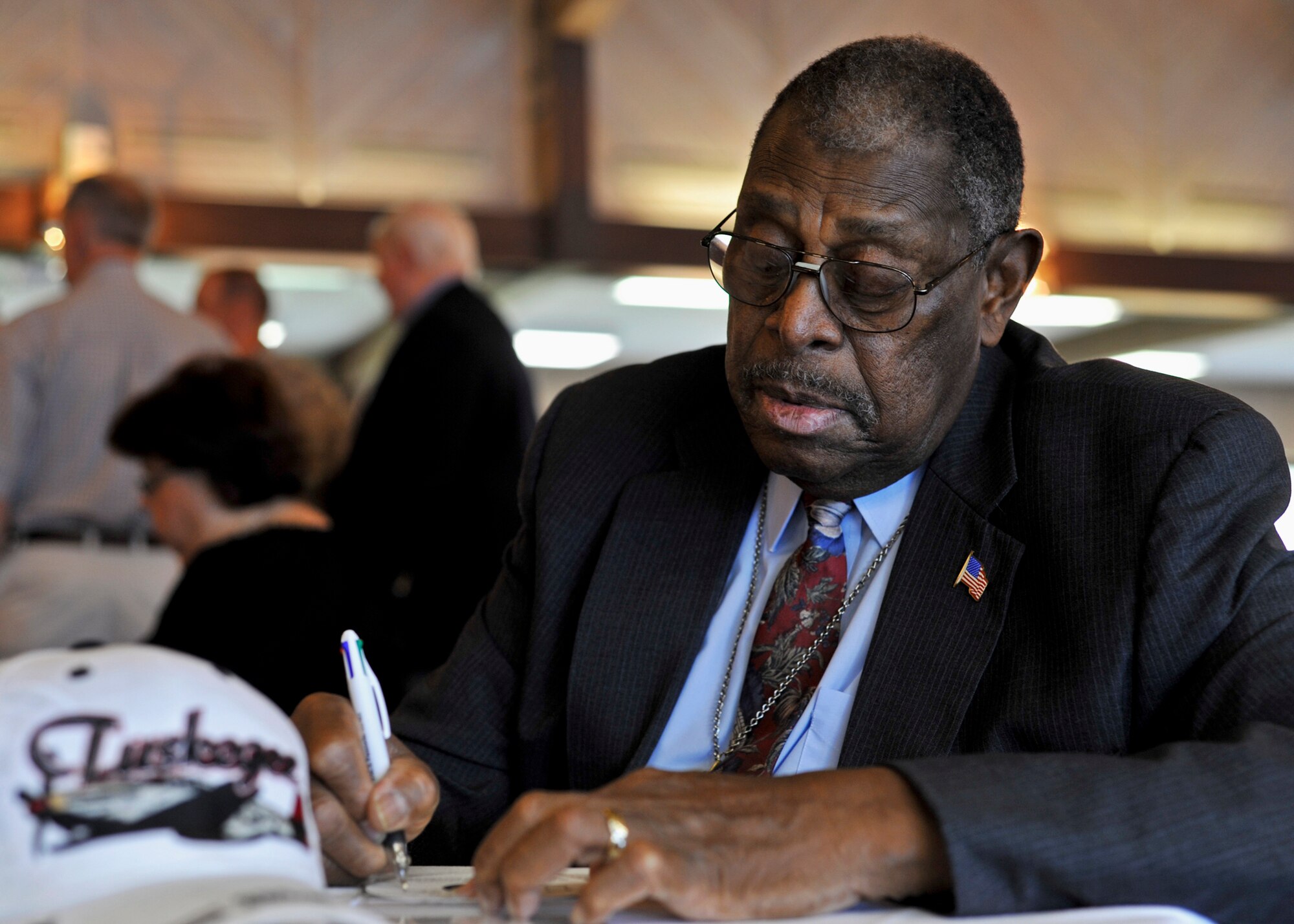 Chief Master Sgt. (ret) Walt Richardson, signs a CD after the ceremony for 89-year-old Charles “Buster” Donnell at the Air Force Enlisted Village, Oct 20.  Chief Richardson, an original member of the famed World War II-era Tuskegee Airmen, was one of the first African-American Airmen tasked to begin integrating the fledgling U.S. Air Force.  (U.S. Air Force photo/Samuel King Jr.)