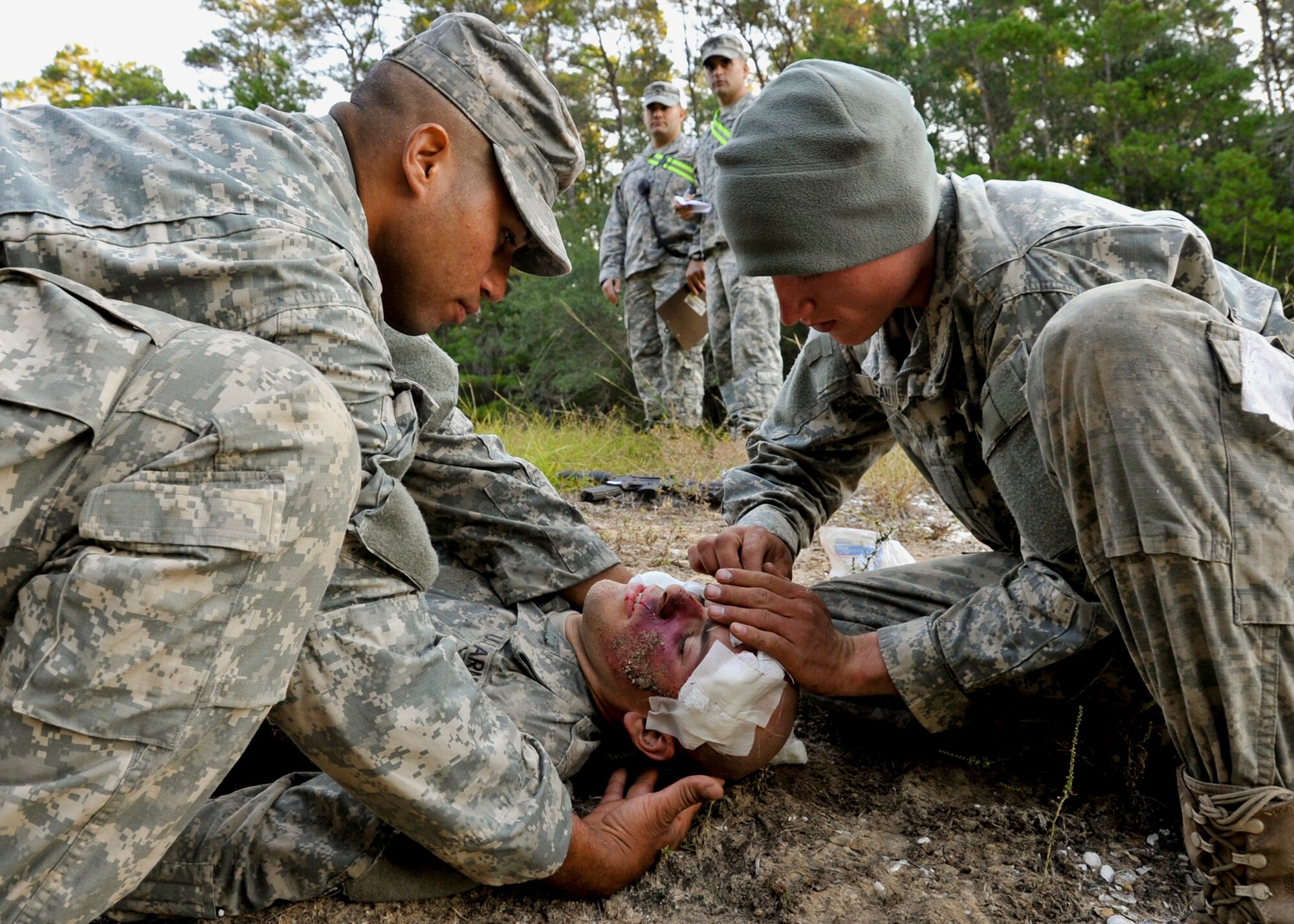 Army Rangers bandage the head wound of a fellow Soldier after a simulated bus accident Oct. 19 while exercise coordinators evaluate their response to the incident played at the entrance to their camp on Eglin Air Force Base. The no-notice exercise simulated an accident involving two cyclists and a bus carrying 6th Ranger Training Battalion students. Soldiers following in the other buses reacted quickly to secure the scene while getting medical support from Eglin and local emergency crews. (U.S. Air Force photo/Samuel King Jr.)