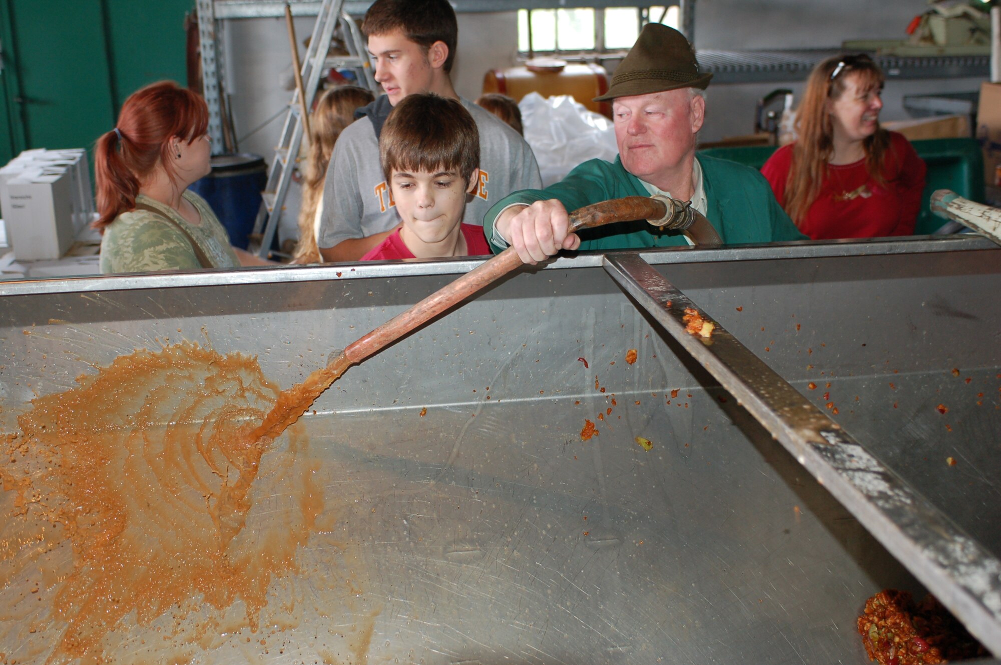 OSANN-MONZEL, Germany--Children from the Spangdahlem Homeschooling Group observe how the vintner, Matthias Sailer rinses out the apple trailer with juice and a steam hose. Together with their parents, children from the Spangdahlem Homeschooling Group recently visited the local Sailer-Cipolla winery in Osann-Monzel, helped vintners collect apples and learned how to make apple cider. (U.S. Air Force photo/Iris Reiff)