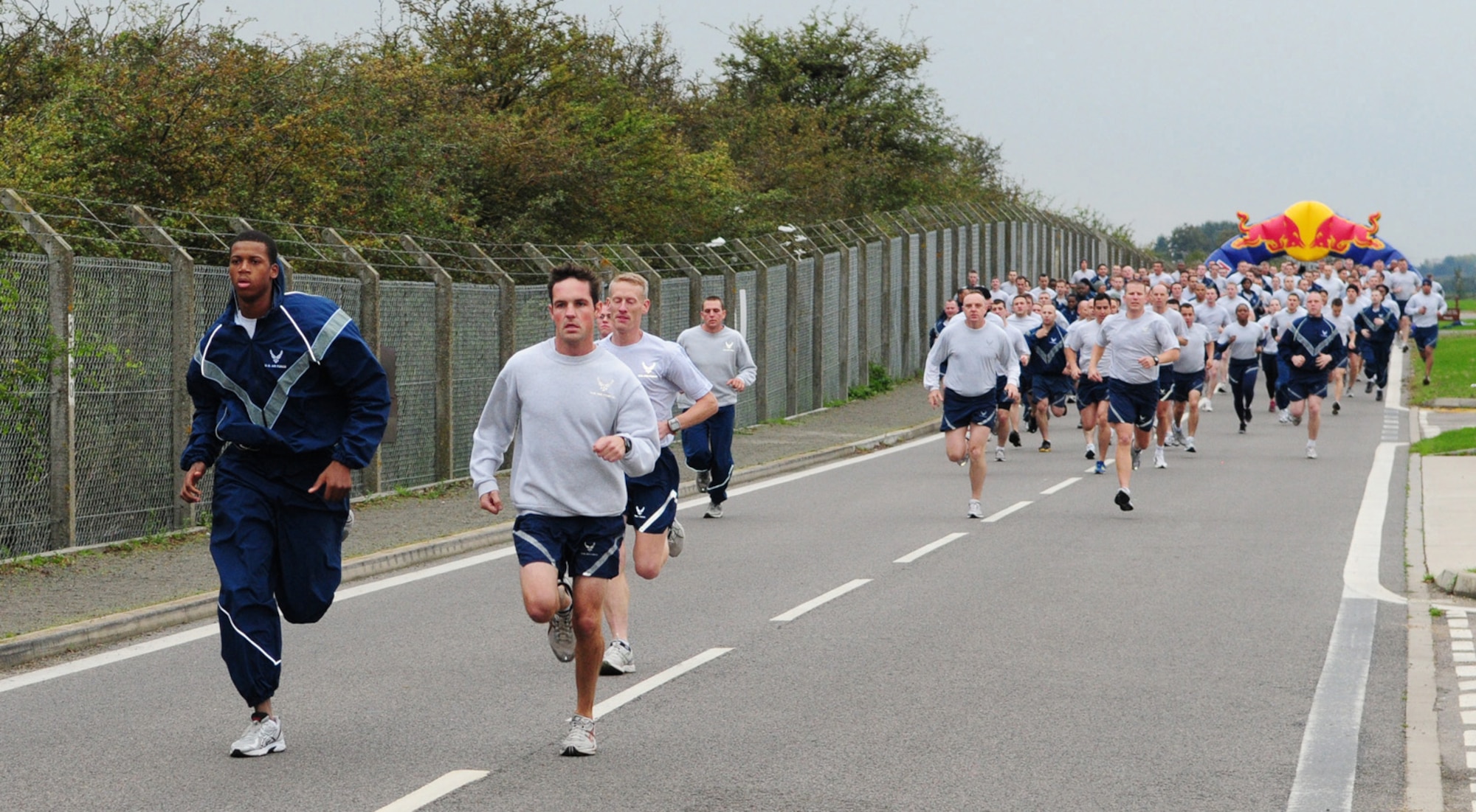RAF MILDENHALL, England -- The first Team Mildenhall runners come racing down Perimeter Road near the Hardstand Fitness Center and Hangar 814 at the monthly wing 5K run Oct. 15. The regular event is held to promote fitness and camaraderie among base members. (U.S. Air Force photo/Karen Abeyasekere)