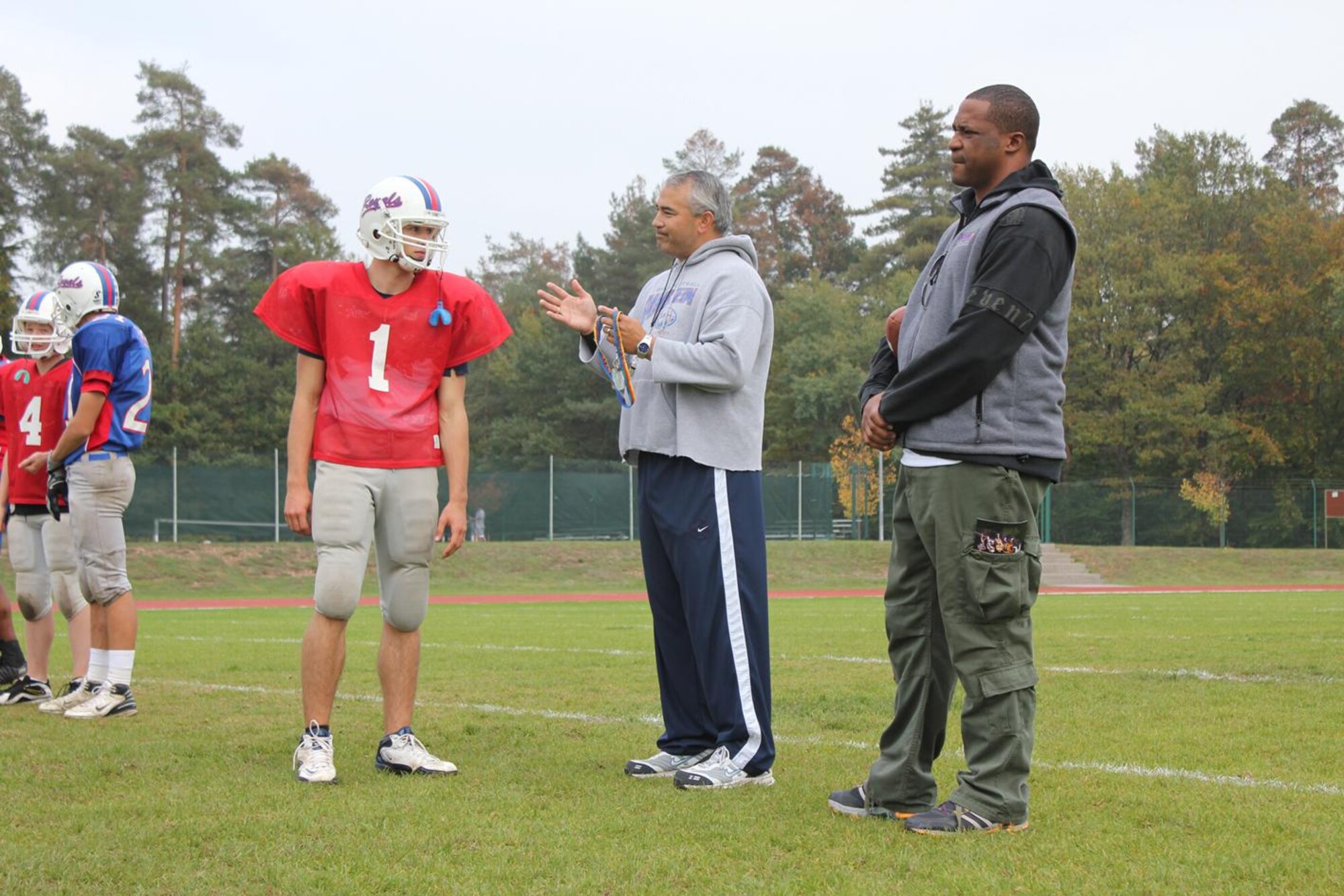 Derrick Mayes, a member of the 1996 Super Bowl championship team the Green Bay Packers and one of the university of Notre Dame's all-time leading receivers, watches Steven Groenheim receive instructions from Coach Carlos Amponin Oct. 7 at Ramstein High School.  My Mayes, who represents the National Collegiate Scouting Association, was at the school to speak with students and parents on dispelling the myths and misconceptions of the college recruiting process. 