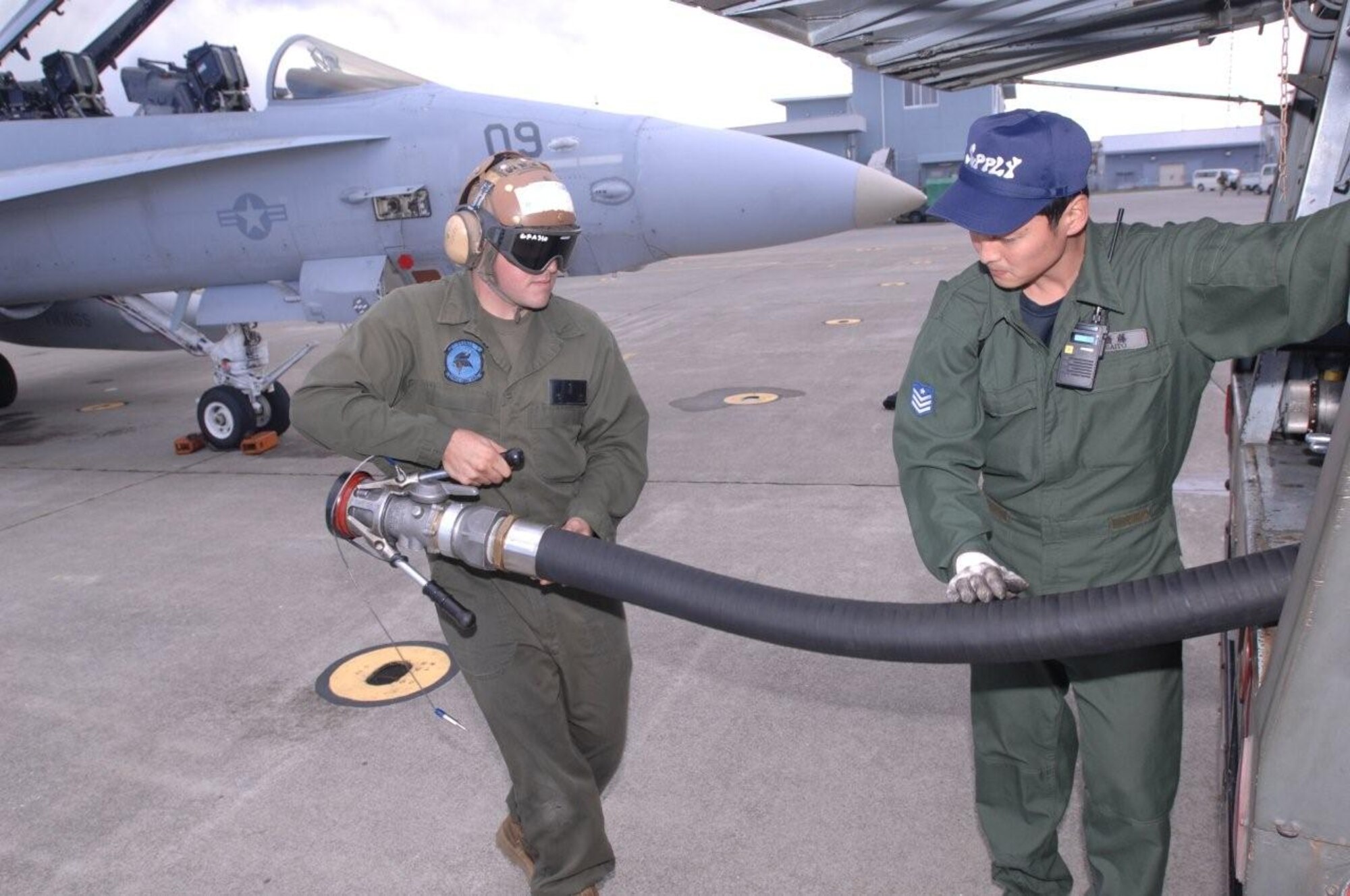 NAVAL AIR FACILITY MISAWA, Japan -- Marine Cpl. Xavier Figueroa, from Marine Fighter Attack Squadron (All Weather) 225, left, returns a fuel line to Japanese Airman 1st Class Kentaro Saito, from the Japanese Air Self-Defense Force (JASDF) following the successful refueling of a Marine F/A-18 Hornet at Misawa Air Base, Oct. 21, 2010. U.S. Marines and Japanese Air Self-Defense Force personnel are taking part in an Aviation Training Relocation (ATR) exercise here with the goal of increasing combat readiness and interoperability between U.S. and JASDF personnel. U.S. Navy photo by Chief Mass Communication Specialist Daniel Sanford) 