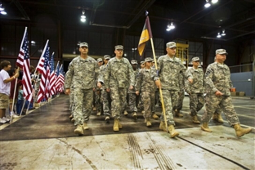 Family and friends hold American flags for soldiers as they march through the doors of a hangar at Stout Field in Indianapolis to meet their loved ones after returning home from a yearlong deployment to Afghanistan, Oct. 20, 2010.  The unit, made up of soldiers from Indiana, Oklahoma and Texas National Guards, specializes in training Afghan farmers in modern farming techniques. The soldiers are assigned to the the 2-19th Agribusiness Development Team.