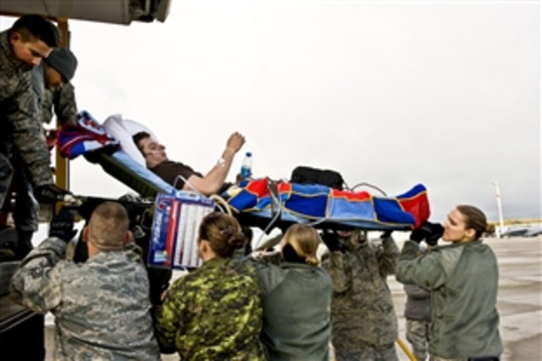 Medical personnel from Ramstein Air Base, Germany, transfer a wounded servicemember from a KC-135 aircraft to a bus that will move him to another medical facility in the area, including Landstuhl Regional Medical Center, Oct 20, 2010. Ramstein averages at least two medical flights per day from deployed locations.