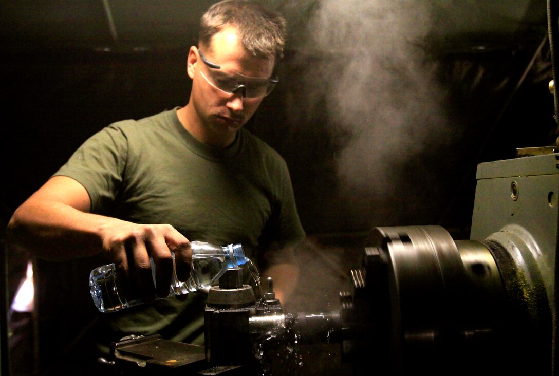 Pfc. Brandon MacKenzie, machinist, 1st Maintenance Co., 1st Maintenance Battalion, Combat Logistics Regiment 15, 1st Marine Logistics Group (Forward), cools off a piece of metal with bottled water after resizing the object, Oct. 21. MacKenzie, a 23-year-old native of Taunton, Mass., is one of approximately 50 Marines assisting Combat Logistics Battalion 3 on Camp Dwyer, Afghanistan.