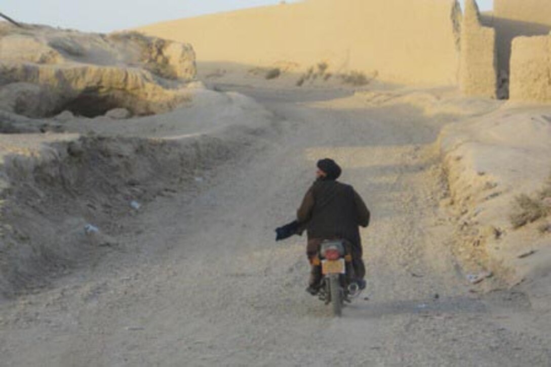 An Afghan man rides his motorcycle over the newly-repaired road completed by Marines with 9th Engineer Support Battalion, 1st Marine Logistics Group (Forward). In addition to repairing four kilometers worth of road, the engineers also improved or replaced several culverts, aiding local farmers in irrigating their fields. The road improvements will improve trafficability for both coalition forces as well as Shir Ghazay residents.