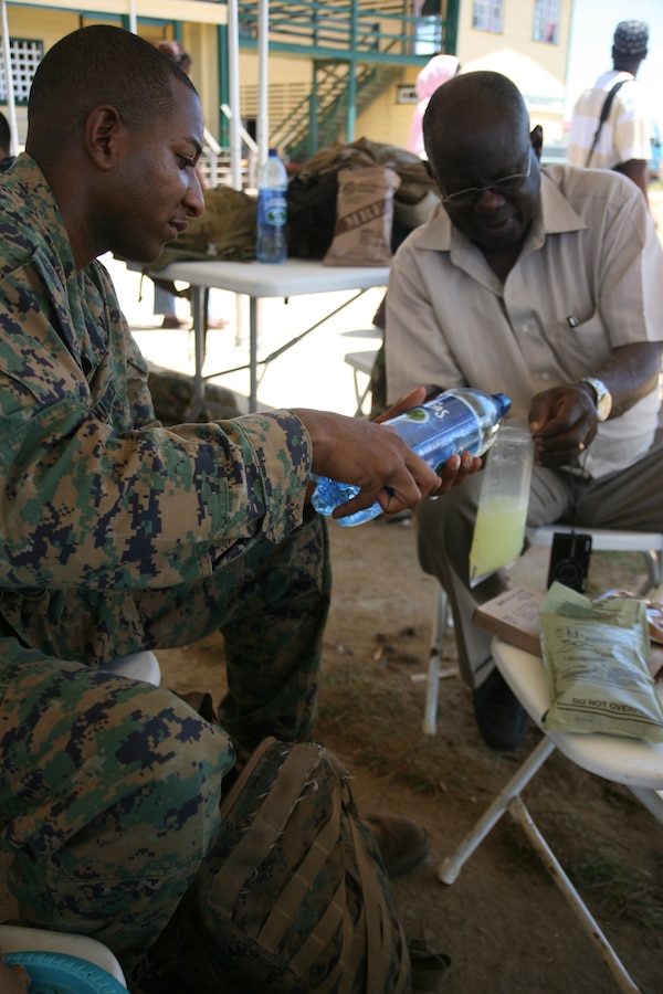 Cpl. John C. Eversley, a motor transportation operator with Special-Purpose Marine Air-Ground Task Force Continuing Promise 2010, pours water into a lemonade solution from his field Meal Ready to Eat to share the beverage with his Guyanese uncle, Thomas Eversley in Rose Hall, Guyana, Oct. 22, 2010. Cpl. Eversley had the unique opportunity to visit with his Guyanese family for an entire day while the civic-humanitarian assistance mission Operation Continuing Promise 2010 that Eversley is currently serving on made a stopover in Guyana for 10 days.