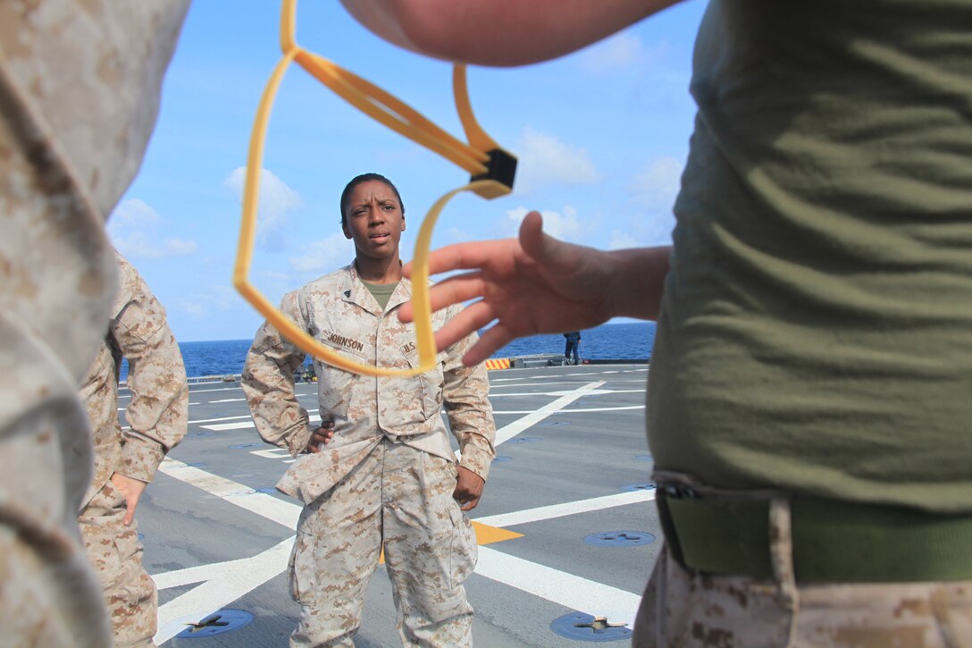 Corporal Brandy Johnson, a Female Engagement Team (FET) member with Combat Logistics Battalion 26, 26th Marine Expeditionary Unit, learns how to use flexi-cuffs during a searching class on the flight deck of USS Ponce, Oct. 22, 2010.  The FET is composed of female Marines who could be called upon to patrol with all male-units to interact with women in countries where women are restricted from speaking with men. 26th MEU is currently embarked aboard the ships of Kearsarge Amphibious Ready Group operating in the 5th Fleet area of responsibility.