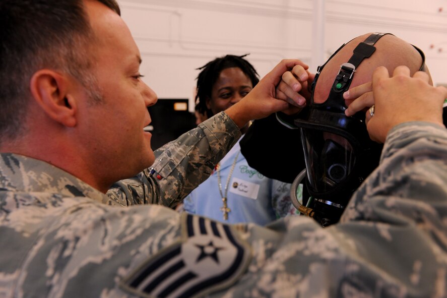 Staff Sgt. Jeremy Johnson, 23rd Component Maintenance Squadron aircraft fuels system, assists David Morales, military spouse, in donning an air supplied respirator during the 23rd Maintenance Group Spouse’s Orientation Day here Oct. 22. Spouses were given the opportunity to interact with military members and the equipment they use daily. (U.S. Air Force photo/Airman 1st Class Benjamin Wiseman)