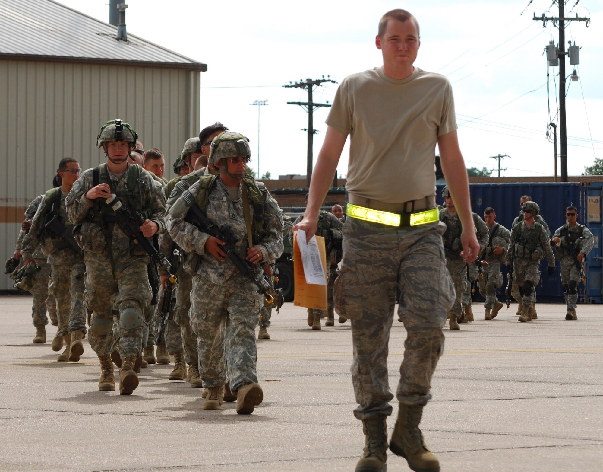 Airman First Class Collin Pinkerton-Morrow, 570th Global Mobility Squadron, leads a group of Soldiers onto the flightline to board a C-130 departing to a forward operating location. (U.S. Air Force Photo/Capt Paradon Silpasornprasit