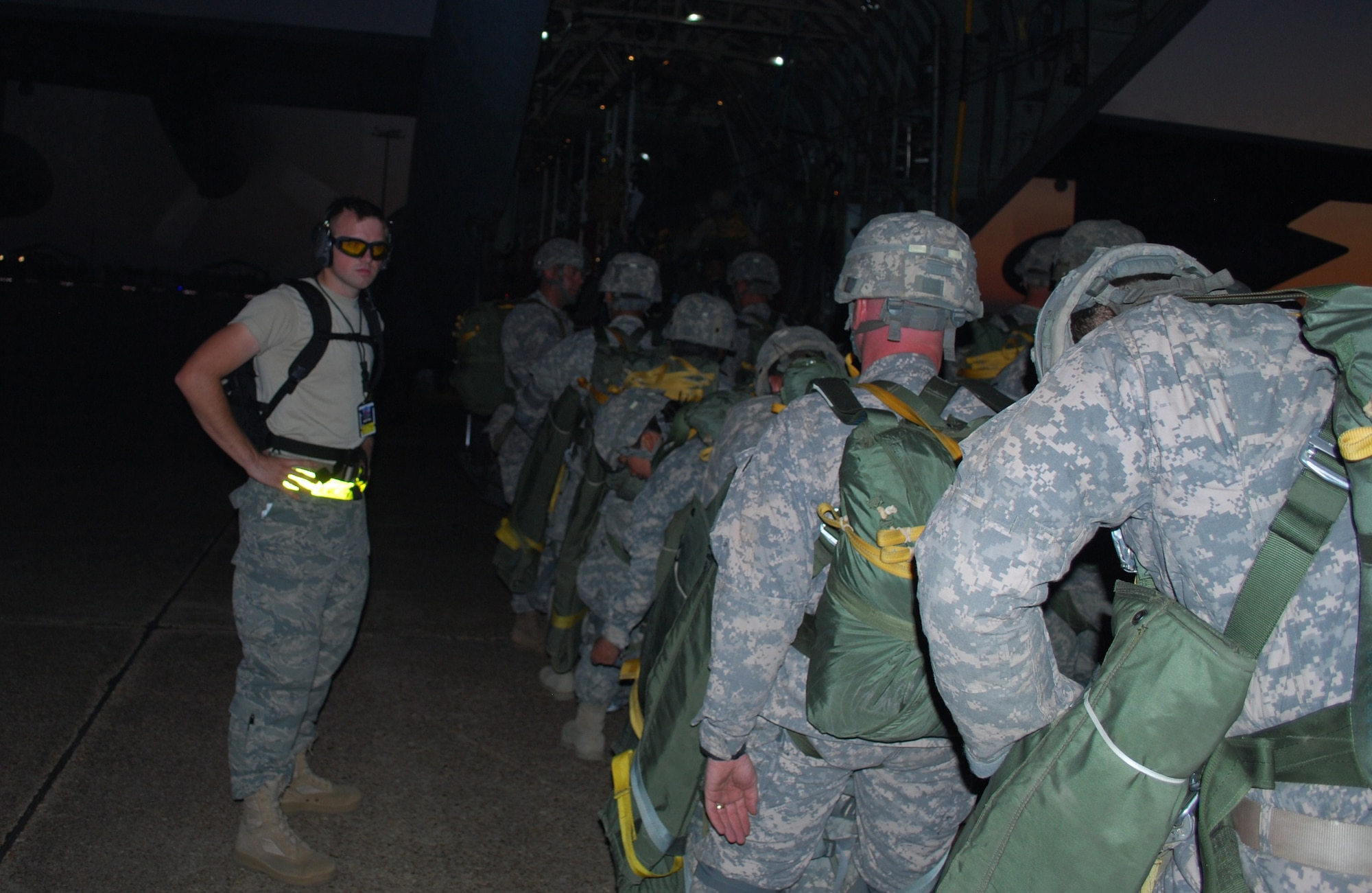 Airman First Class Brian Lavergne, 570th Global Mobility Squadron, helps guide Army paratroopers onto an awaiting C-130 aircraft. (U.S. Air Force Photo/Capt Paradon Silpasornprasit)

