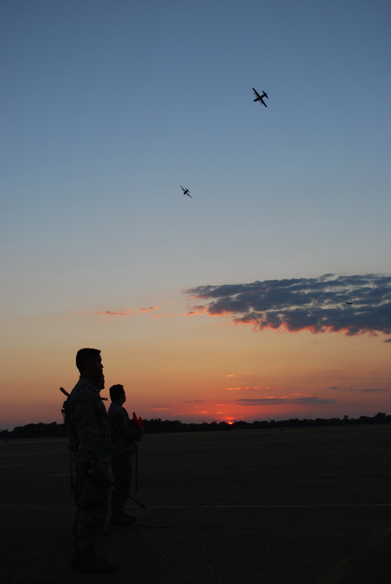Members of the 615th CRW look on as a formation of C-130s arrives to transport 1,700 paratroopers to the drop zone. (U.S. Air Force Photo/Capt Paradon Silpasornprasit)

