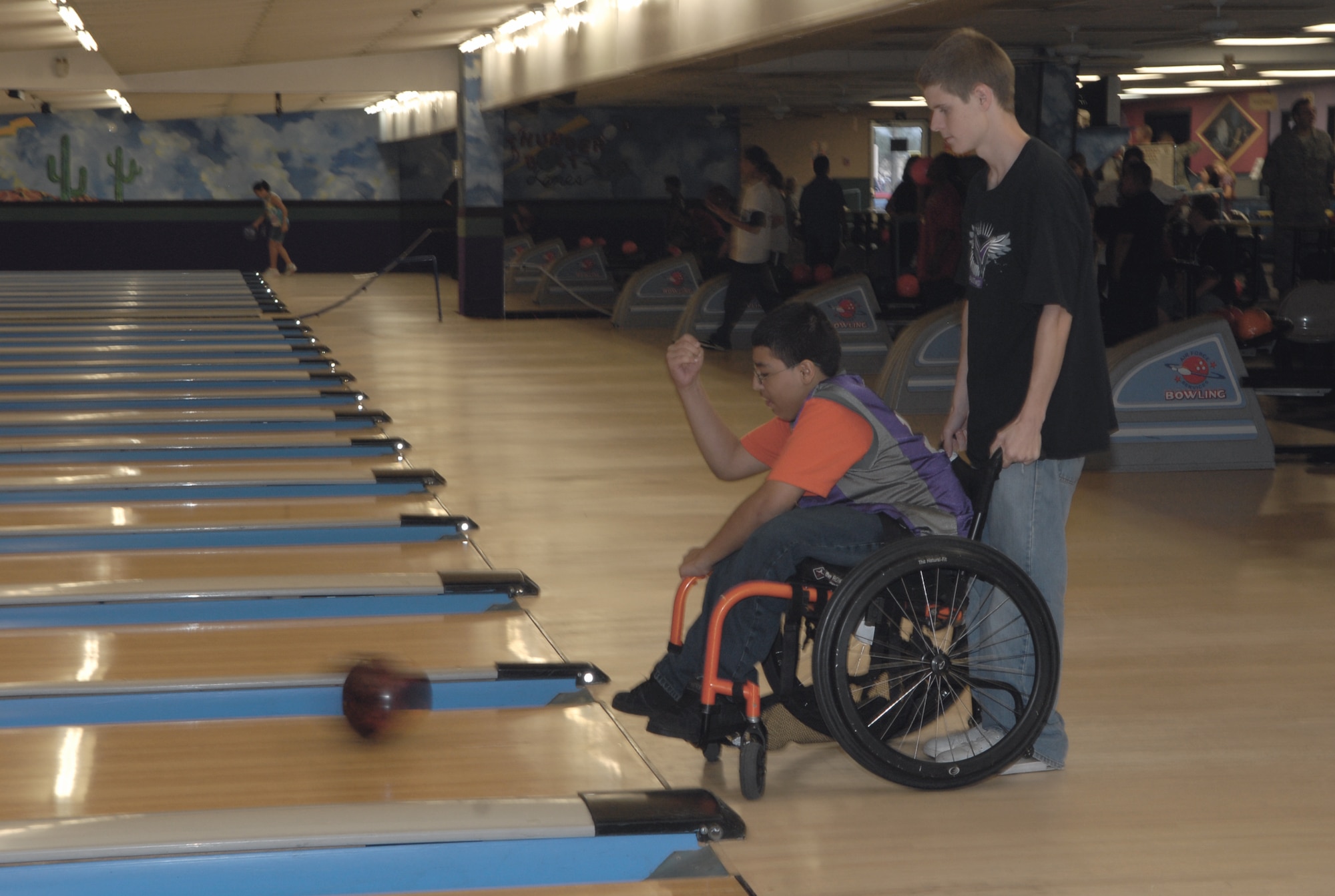 Abel Perez bowls from his wheel chair with help from his classmaste, A.J. Graff.  Both are students at Valley Vista High School.  (U.S. Air Force photo/Airman 1st Class Melanie Holochwost)