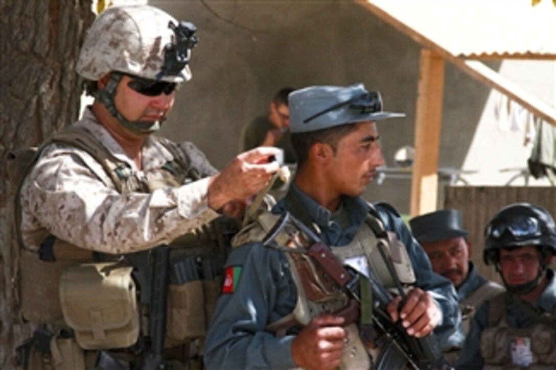 U.S. Marine Corps Capt. Dave Wright (left), with Police Mentoring Team 1, 3rd Battalion, 5th Marine Regiment, Regimental Combat Team 2, adjusts an Afghan National Police officer's gear at Forward Operating Base Jackson before a patrol in Sangin Valley, Afghanistan, on Oct. 7, 2010.  The battalion was one of the combat elements of Regimental Combat Team 2, whose mission was to conduct counterinsurgency operations with International Security Assistance Forces.  