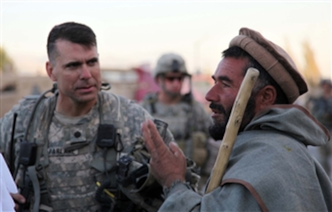U.S. Army Lt. Col. Matthew McFarlane (left), commander of 1st Battalion, 503rd Infantry Regiment, 173rd Airborne Brigade Combat Team, talks with the night security guard at the Salar Bazaar, Wardak province, Afghanistan, on Oct. 18, 2010.  