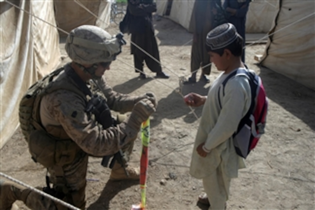 U.S. Marine Corps 1st Sgt. Jonathon Wyble, with Fox Company, 2nd Battalion, 6th Marine Regiment, Regimental Combat Team 1, assists an Afghan child with his kite in Marjah, Afghanistan, on Oct. 10, 2010.  The regiment was deployed to Helmand province to support the International Security Assistance Force.  