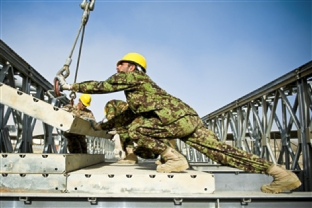 Afghans soldiers bring elements of a temporary bridge together on Camp Gazi, Afghanistan. NATO and coalition forces are training Afghan soldiers how to assemble and disassemble the bridges for future use around the country.