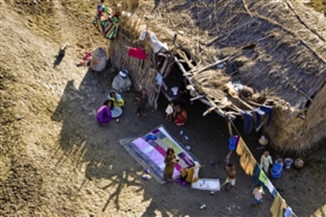 Pakistanis affected by floods watch as a U.S. Marine Corps CH-46 Sea Knight helicopter flies overhead, transporting flood-relief supplies to an aid distribution site near Pano Aqil Cantonment, Pakistan, Oct. 21, 2010. The U.S. Marine Corps’ 15th and 26th Marine Expeditionary Units have been operating CH-46 Sea Knight and CH-53 Super Stallion helicopters in Sindh province since early September, bringing relief supplies to those in need.