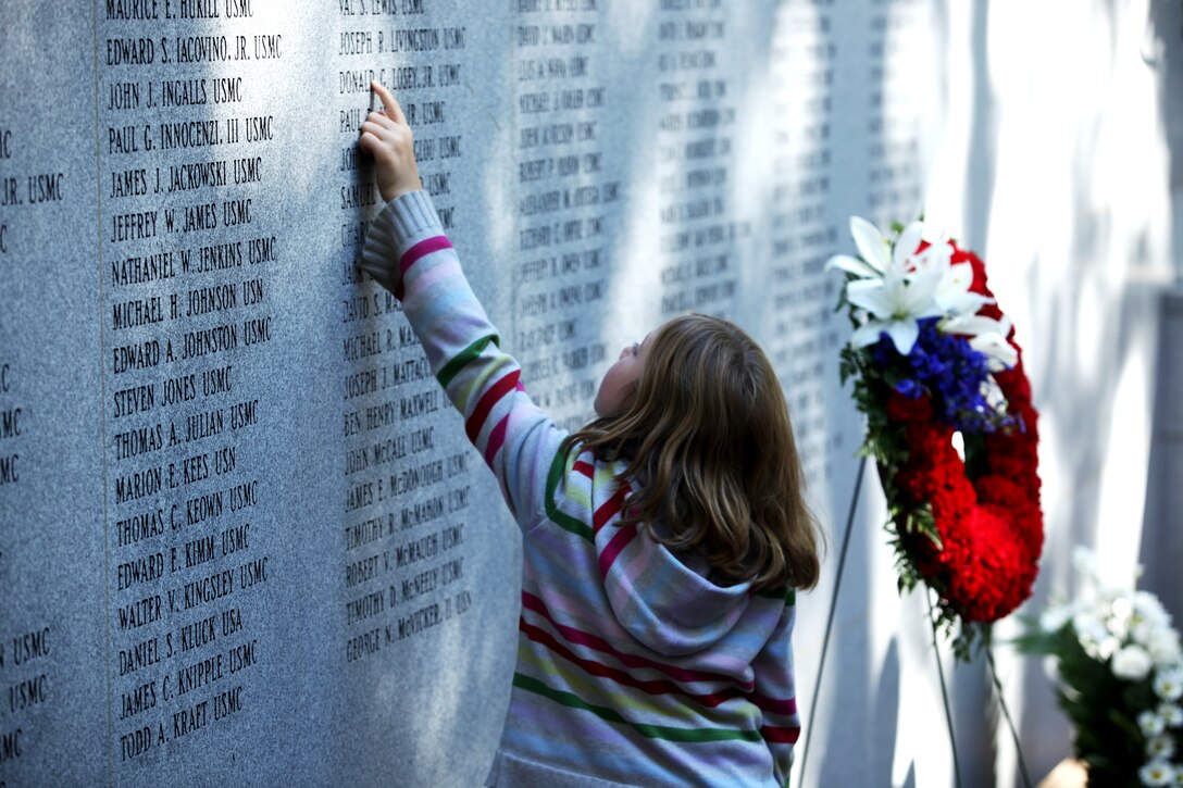 A young girl recognizes a name on the Beirut Memorial wall and reaches out to touch it during the commemoration of the 24th annual Beirut Memorial Observance Ceremony, held at the Beirut Memorial, Jacksonville, N.C. Oct. 23. It is a tradition to pay service members who gave the ultimate sacrifice respects by touching their names and vowing never to forget.