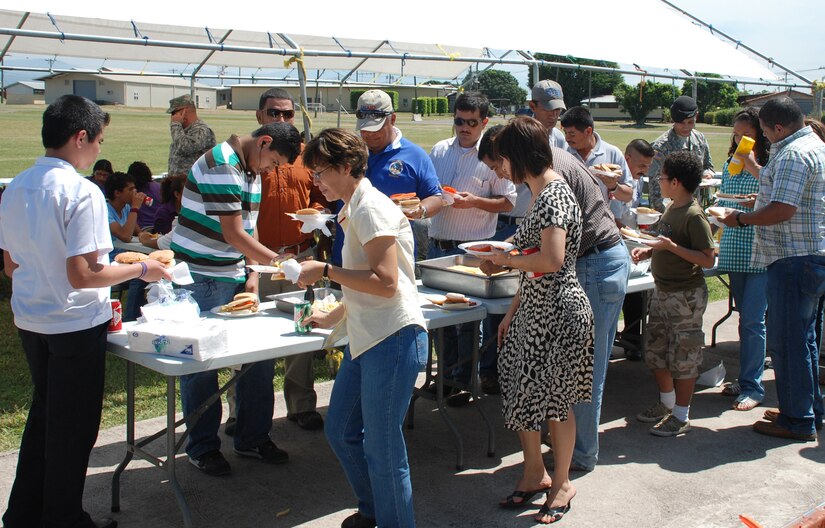 SOTO CANO AIR BASE, Honduras --  Foreign service nationals, their family members and U.S. servicemembers grab some barbecued lunch during FSN Family Day here Oct. 22. Joint Task Force-Bravo and Honduran Air Force Academy leadership hosted the day, offering FSNs and their family members tours of base facilities, lunch, games and an awards ceremony. (U.S. Air Force photo/Capt. John Stamm)