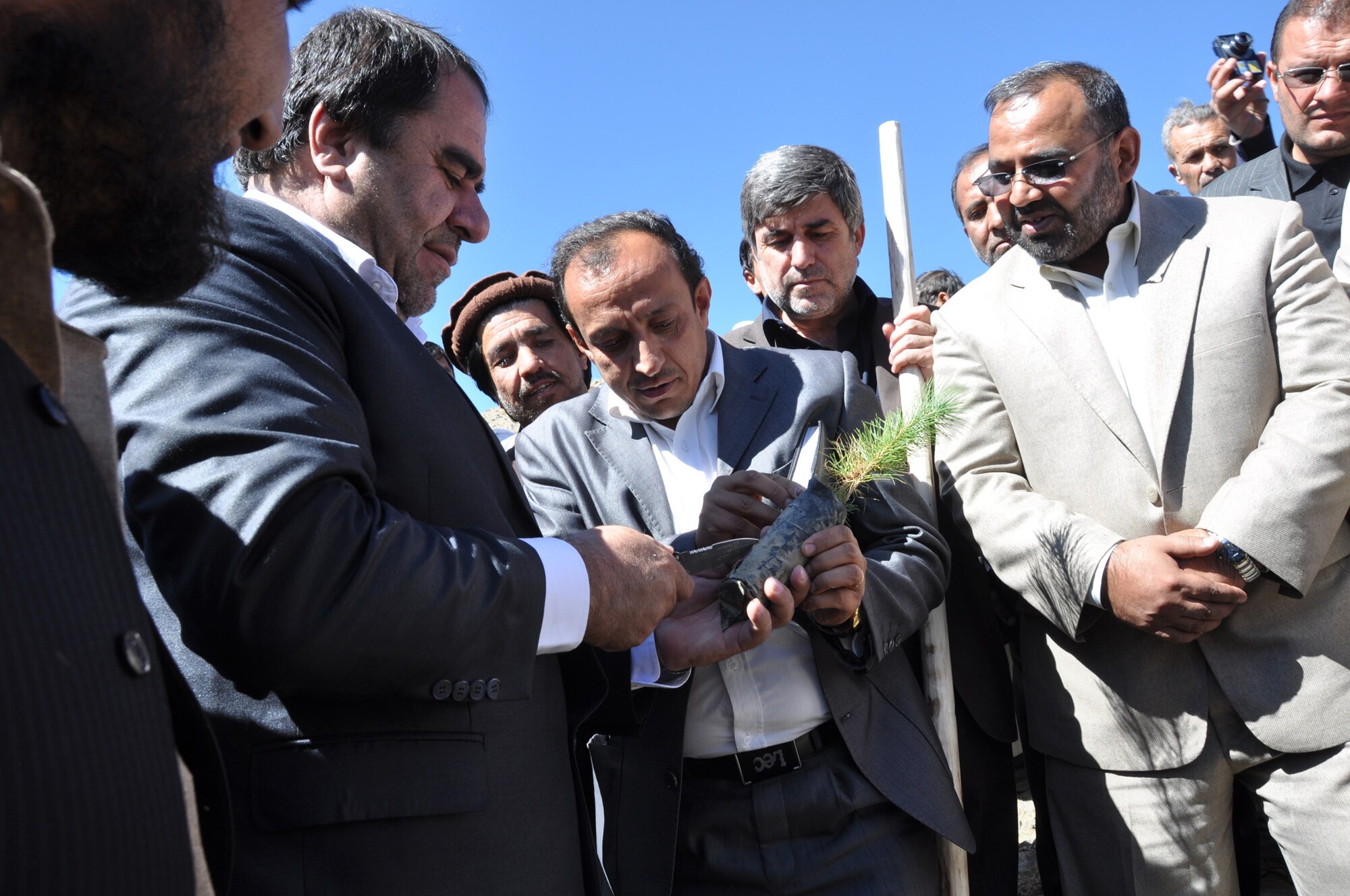 Hashmatulah Enayat, Panjshir Director of Agriculture, Irrigation and Livestock, hands Panjshir Gov. Keramuddin Keram the first seedling to be planted in the Panjshir greenbelt project. A groundbreaking ceremony was held on a hillside near Massoud?s Tomb in Bazarak Oct. 10. 35,000 trees will be planted throughout the province as part of a reforestation project over the next three months. (U.S. Air Force Photo by 1st Lt. Holly Hess, Panjshir PRT Public Affairs)