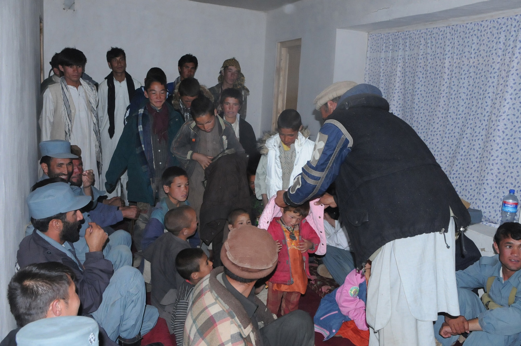 PANJSHIR PROVINCE, Afghanistan ? A village elder from Astana village helps children try on new winter coats, Oct. 6.  Members of the Panjshir Provincial Reconstruction Team hiked 12 kilometers to the remote village of Astana to deliver humanitarian aid in the form of winter coats donated by family and friends of the PRT.  The village of Astana isn?t reachable during the winter months due to large amounts of snow.  (USAF Photo by: Tech Sgt Sean Mateo White, PRT Panjshir photographer)(released)