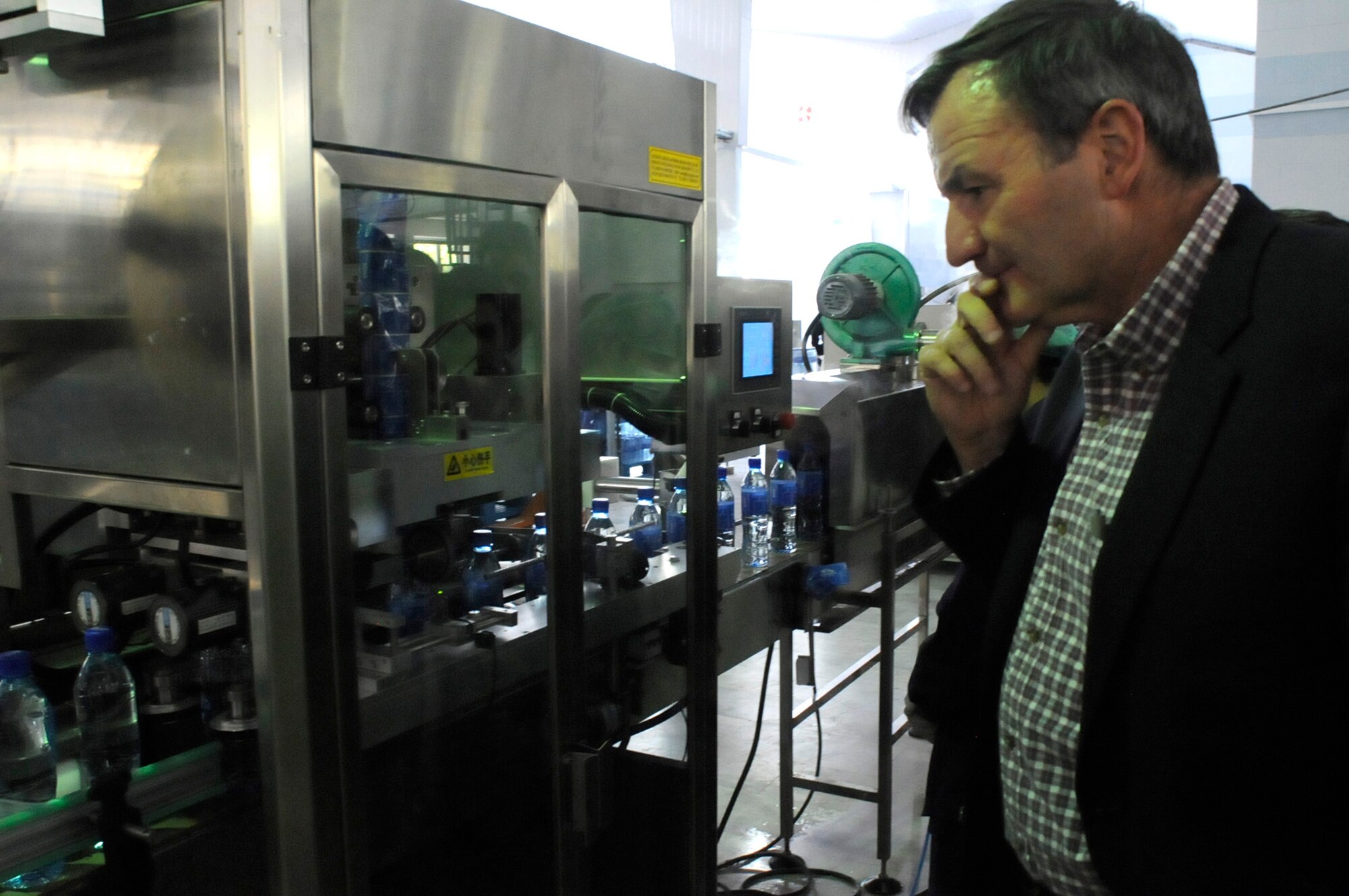 Karl Eikenberry, the U.S. Ambassador to Afghanistan, looks at a moving conveyer belt in the Panjshir water-bottling plant in the Khenj District. Ambassador Eikenberry visited the province to meet with the Panjshir Provincial Reconstruction Team and provincial government officials in order to discuss various provincial issues. (U.S. Air Force Photo by Tech. Sgt. Sean White, Panjshir PRT Public Affairs Photographer)