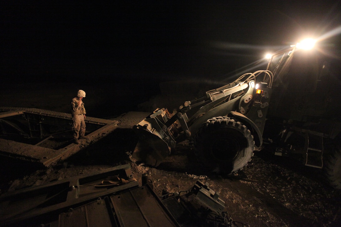Cpl. Kevin S. Major, heavy equipment noncommissioned officer with Bridge Platoon, Company A, 9th Engineer Support Battalion, 1st Marine Logistics Group (Forward), guides a bulldozer during a bridge replacement project in Marjah, Afghanistan, Oct. 23. The Marines removed an old medium girder bridge and replaced it with a newer one, to be used by coalition forces and local nationals.