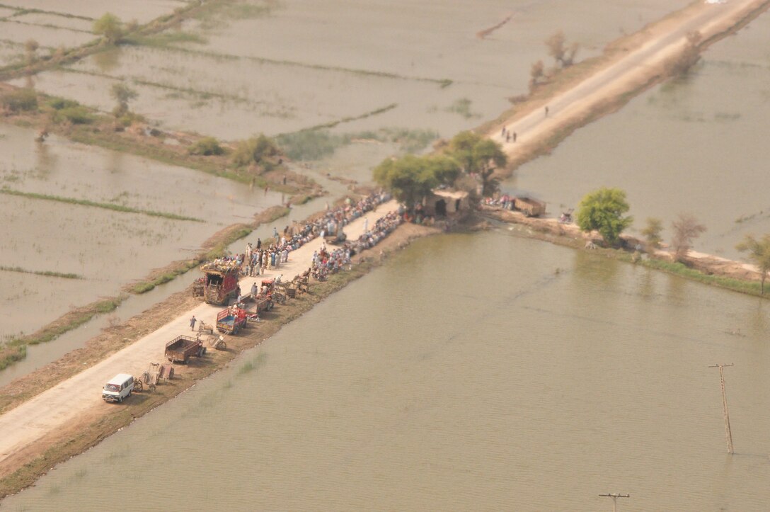 Pakistanis wait for U.S. Marine Corps CH-53 Super Stallions with 26th Marine Expeditionary Unit carrying flood relief supplies to land at a World Food Programme aid distribution site Oct. 24 near Pano Aqil Cantonment, Pakistan. The U.S. Marine Corps’ 15th and 26th MEUs have been operating CH-46 Sea Knight and CH-53 Super Stallion helicopters in the Sindh province since early September bringing relief supplies to those in need. Since Aug. 5, U.S. military helicopters have transported more than 12 million pounds of supplies. (Official U.S. Air Force photo by SSgt Kali Gradishar)(Released)