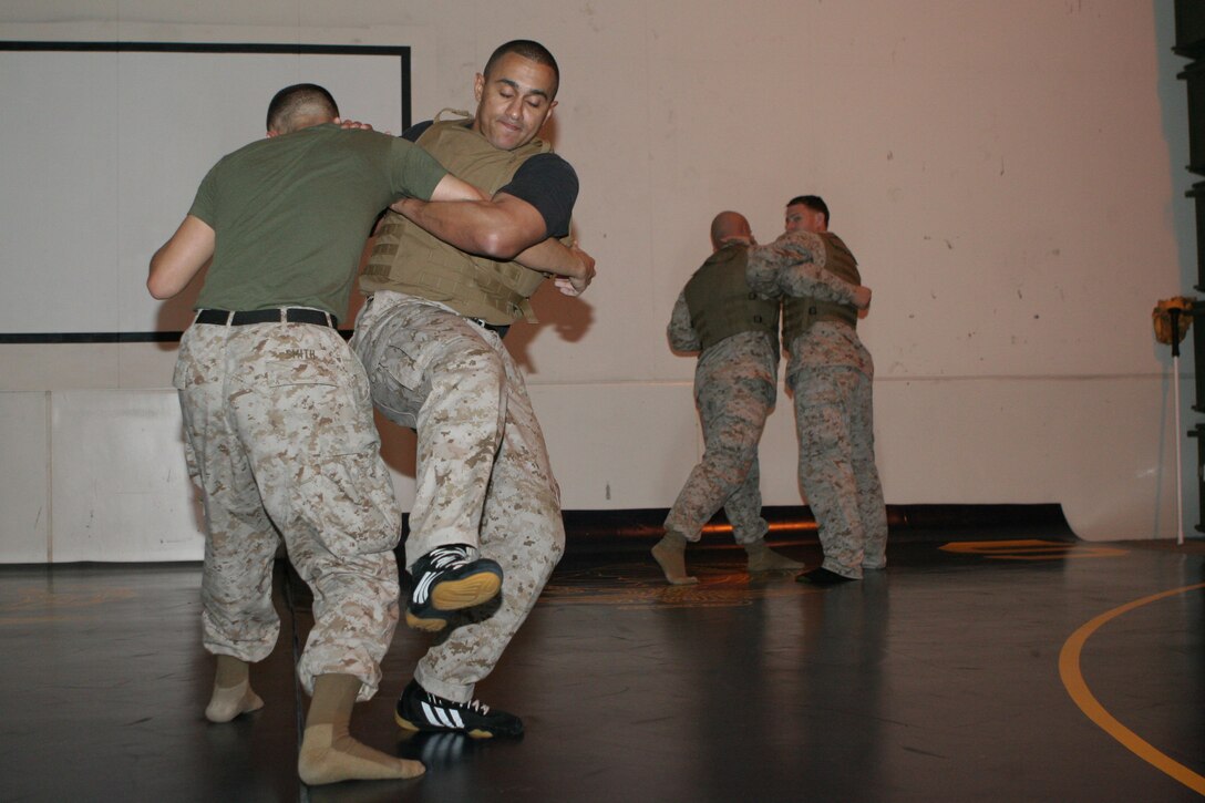 Danilo A. McCabe, a Marine Corps Martial Arts Instructor-Trainer, performs a proper take-down using the course corpsman Jesse L. Smith as a dummy opponent during a Marine Corps Martial Arts Instructors Course period of instruction in the Marine Wing Support Squadron 171 warehouse here Oct. 25. The majority of the course training was originally scheduled at Penny Lake Fields but was changed due to the weather.