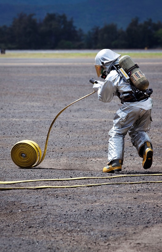Sgt. Conraddo Jonse, a turret operator with Aircraft Rescue Firefighting, Marine Corps Air Station Kaneohe Bay, Hawaii, unrolls a hose in preparation for burn training near the MCAS flight line, Oct. 24, 2010. Once per month, ARFF uses the Mobile Aircraft Firefighting Training Device, a stainless steel aircraft mock-up, to practice realistic firefighting scenarios. After creating scenarios, operators burn propane on target areas of the MAFTD, such as the cabin, cockpit, and engines, while a team of firefighters moves in to extinguish the fire.