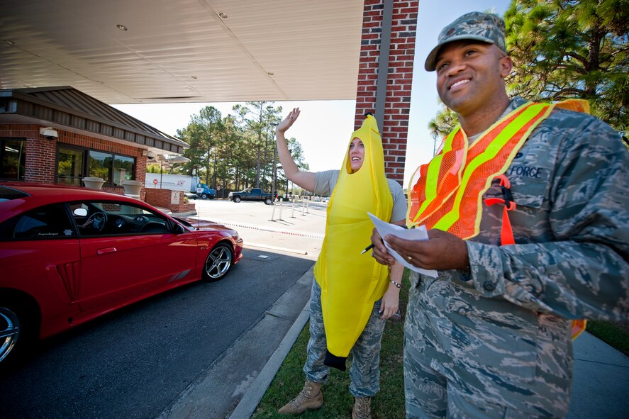 MOODY AIR FORCE BASE, Ga. -- Tech. Sgt. Amanda Turner, 23rd Maintenance Operations Squadron unit training manager, and Maj. Maurice Lee, 23rd MOS commander, conduct seatbelt checks here Oct. 22. Sergeant Turner and Major Lee received top votes as part of their squadron’s “Dirty Deeds” fundraiser contest. The two greeted more than 100 base personnel while playfully reminding them to stay safe during the weekend. (U.S. Air Force photo/Senior Airman Jamal D. Sutter)