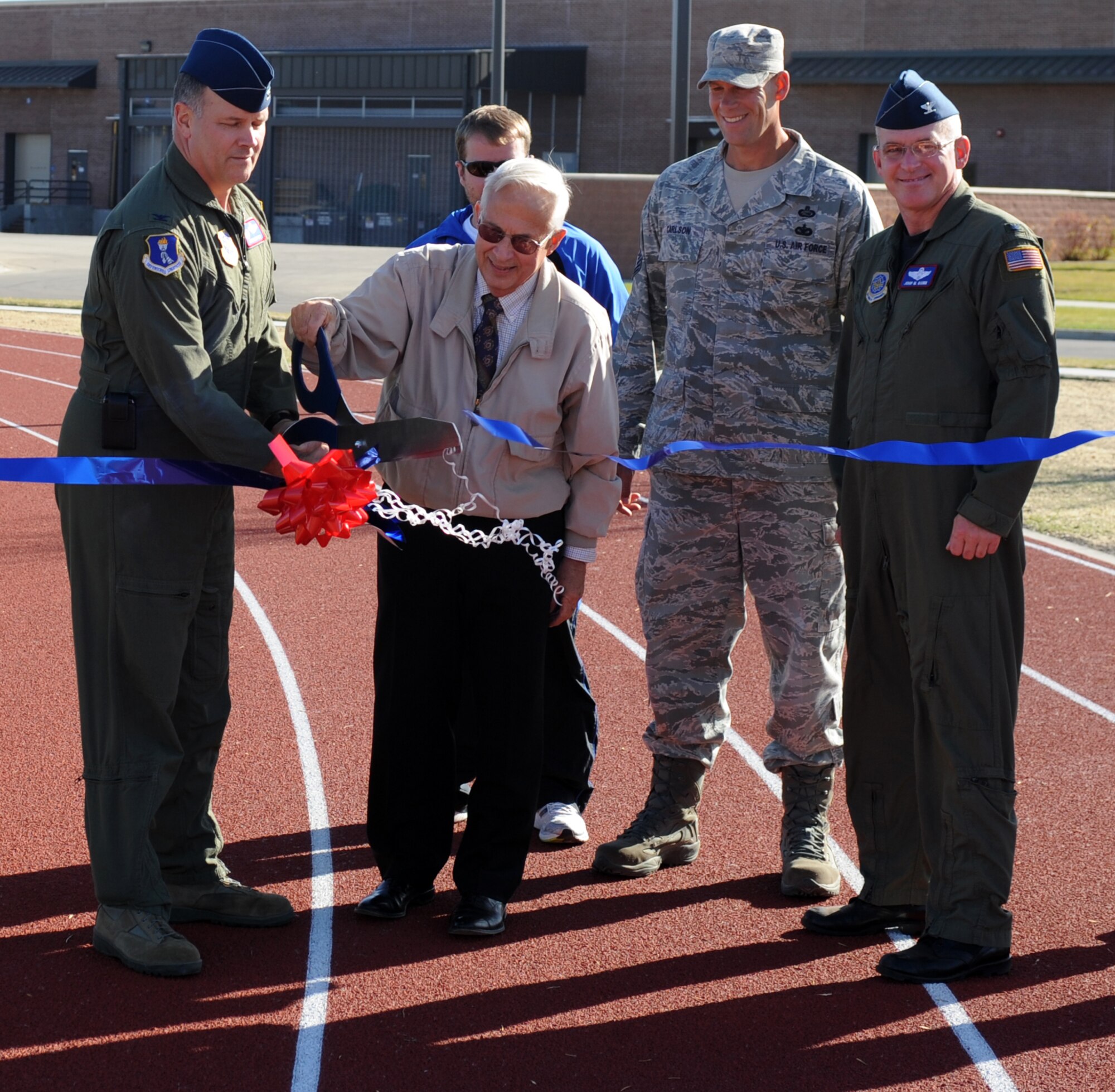 Col. Don Shaffer (left), 319th Air Refueling Wing commander, and Jim Bradshaw (center), honorary ambassador number six to Grand Forks Air Force Base, cut a ribbon to signify the outdoor track is now officially open Oct. 22, as Chief Master Sgt. David Carlson (second to right), 319th ARW command chief and Col. John Quinn (right), 319th ARW vice-commander, look on during a ceremony on base. Construction on the track began late spring and concluded in early October. The track is a quarter mile and features pull-up and sit-up bars. (U.S. Air Force photo by Staff Sgt. Suellyn Nuckolls) 
