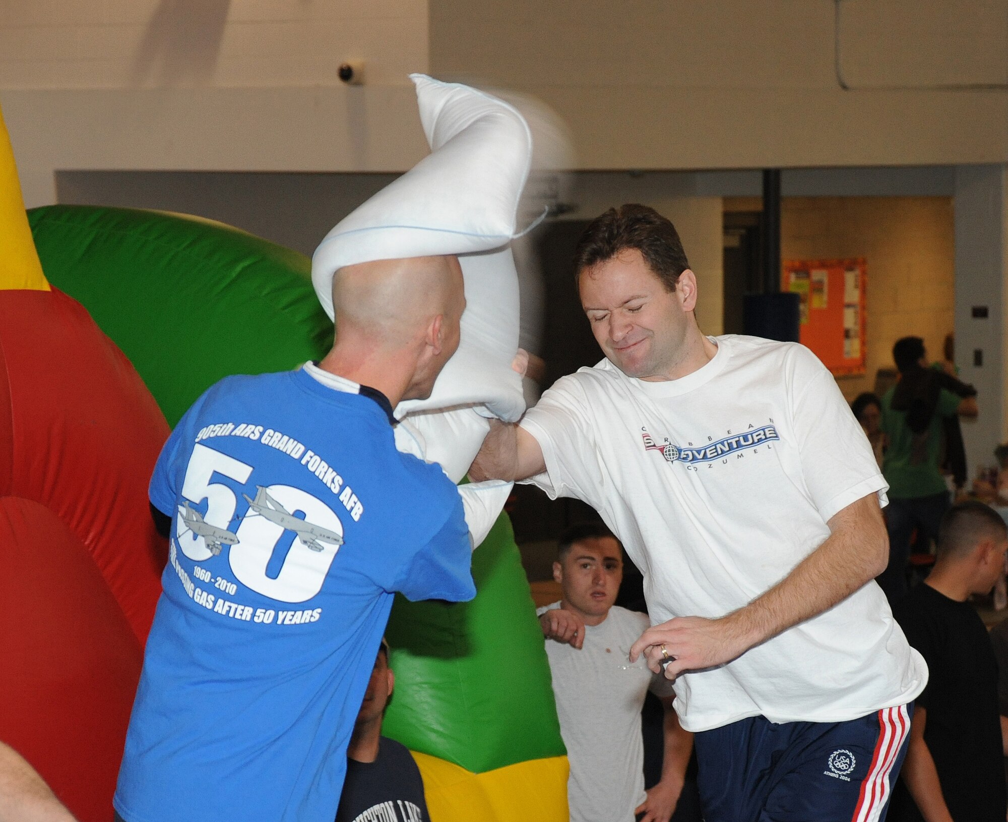 Lt. Col. Brandon Hart, 319th Air Refueling Wing judge advocate, hits Lt. Col. Noel Bradford, 905th Air Refueling Squadron commander, with a pillow during a log jousting event Oct. 21 during Fall Fest on Grand Forks Air Force Base, N.D. In the log jousting event, members from competing squadrons balanced on a log and tried to knock their opponent off. Fall Fest included various events to boost the morale of servicemembers and their families. The 319th Operations Support Squadron won the grand prize drawing of $300. (U.S. Air Force photo by Tech. Sgt. Johnny Saldivar)