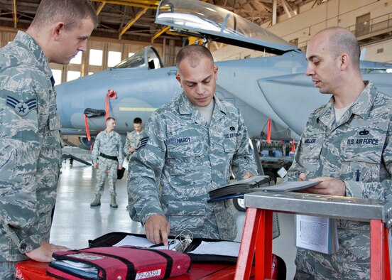 Staff Sgt. Michael Hardy, 46th Maintenance Squadron, and other evaluators review their notes prior to announcing the winner of the quarterly weapons load competition, Oct 22.  Load crews are judged in four areas:  dress and appearance, knowledge of their specialty, tools and equipment, and accuracy, safety and reliability of the actual weapons load.  The Blue AMU team of Staff Sgt. Alison Kline, Senior Airman Krystle Orth, and Senior Airman Ryan Corley won the competition with a time of 38 minutes, 22 seconds.  (U.S. Air Force photo/2nd Lt. Andrew Caulk.)