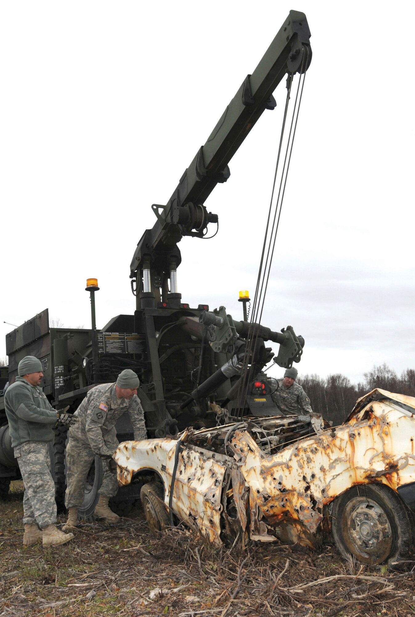 Soldiers of the 207th Combat Support Company, Alaska Army National Guard, (Left to Right) Staff Sgt. Joseluis Villasenor, wheeled vehicle mechanic, Staff Sgt. Edwin Brunner, motor transport operator, and Spc. Ryan Graney, wheeled vehicle mechanic, release the Heavy Expanded Mobility Tactical Truck Wrecker crane hook from a rusted vehicle at Goose Bay State Game Refuge, Sunday. (U.S. ANG photo/Spc. Michelle Nash)