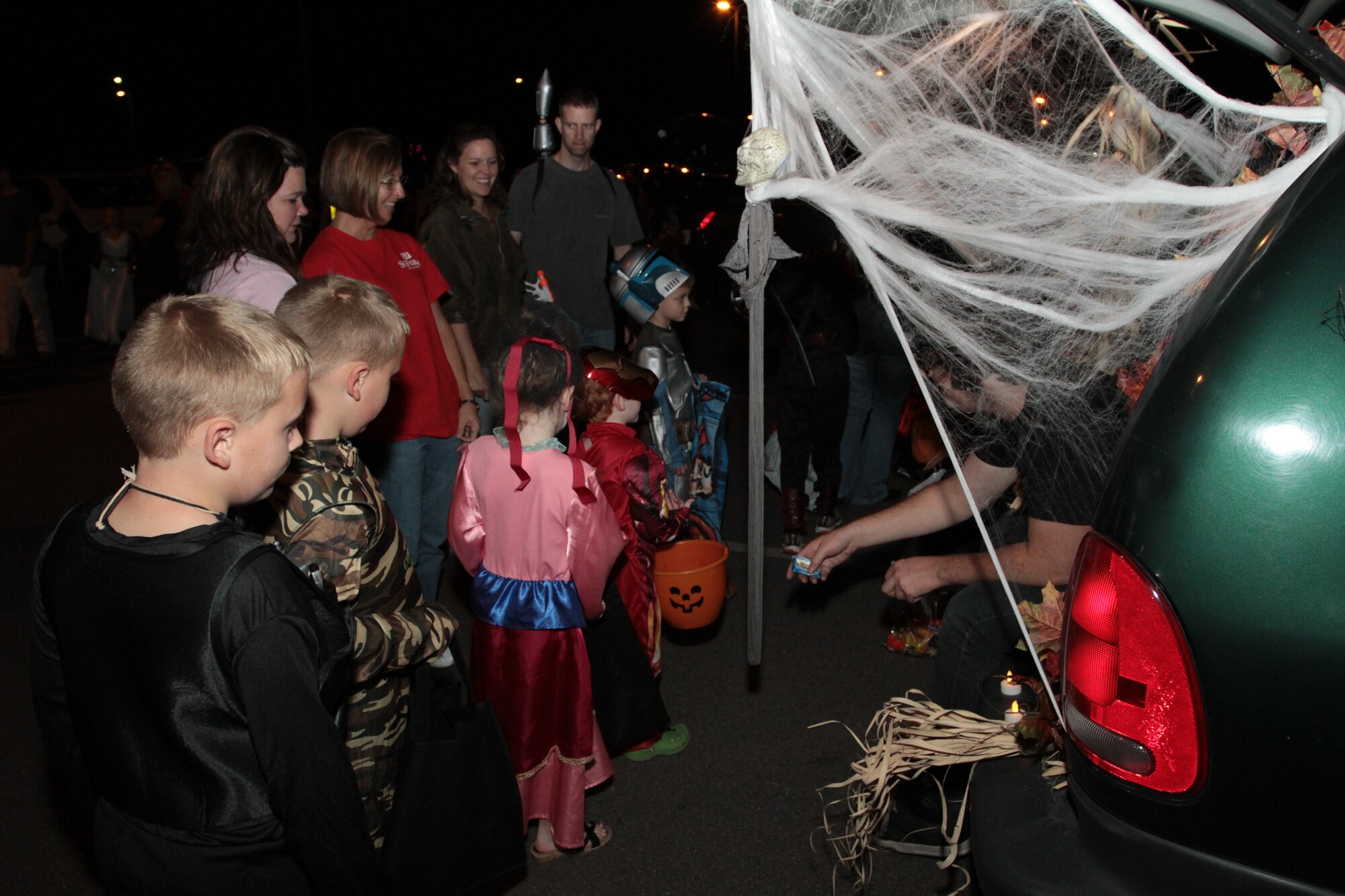 (Right) Josh Horne, son of Lt. Col. Debbie Horne, 19th Force Support Squadron commander, hands candy to children in costumes from the back of a van Oct. 23 during the 2nd Annual Trunk-or-Treat. The event, sponsored by the Little Rock Spouses’ Club, included a number of vehicle trunks decorated for Halloween with candy stations and was a safe alternative to trick-or-treating house to house. (U.S. Army photo by Spc. Jared Sollars)