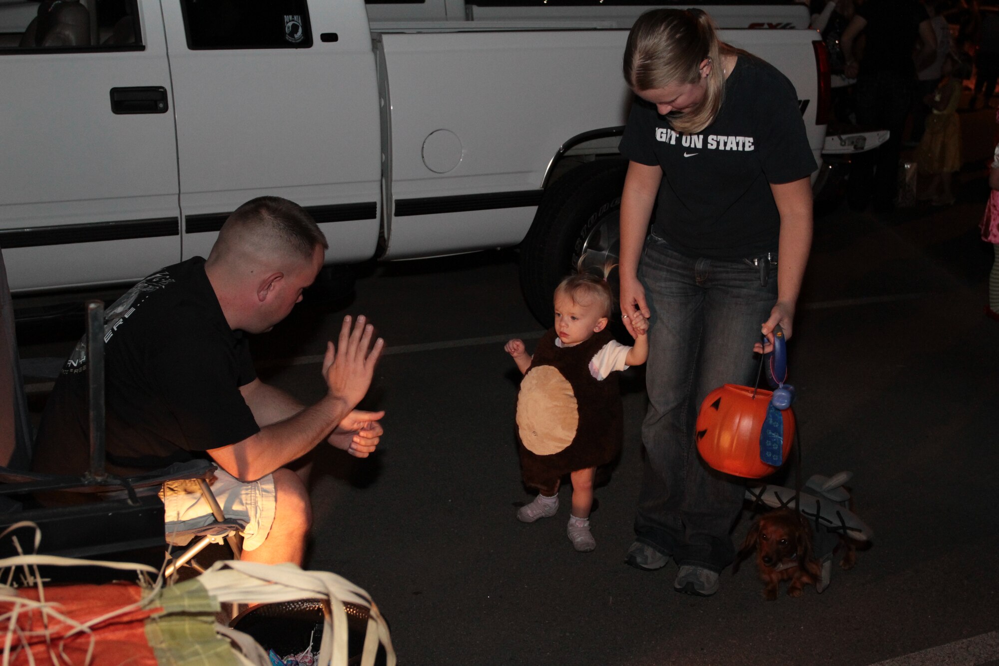 (Left) Tech. Sgt. Michael Carnahan, 19th Aircraft Maintenance Squadron avionics technician, greets 1-year-old Annabel Campbell, daughter of Jessica Campbell and Matthew Campbell, 19th Operations Support Squadron; and their dog, Frances, Oct. 23 during the base’s Trunk-or-Treat. The event was a safe alternative to trick-or-treating house to house. (U.S. Army photo by Spc. Jared Sollars)
